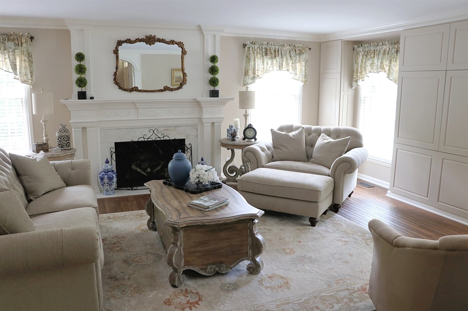 A fireplace with marble surround and fluted mantel is the centerpiece to the living room and is flanked by two windows.