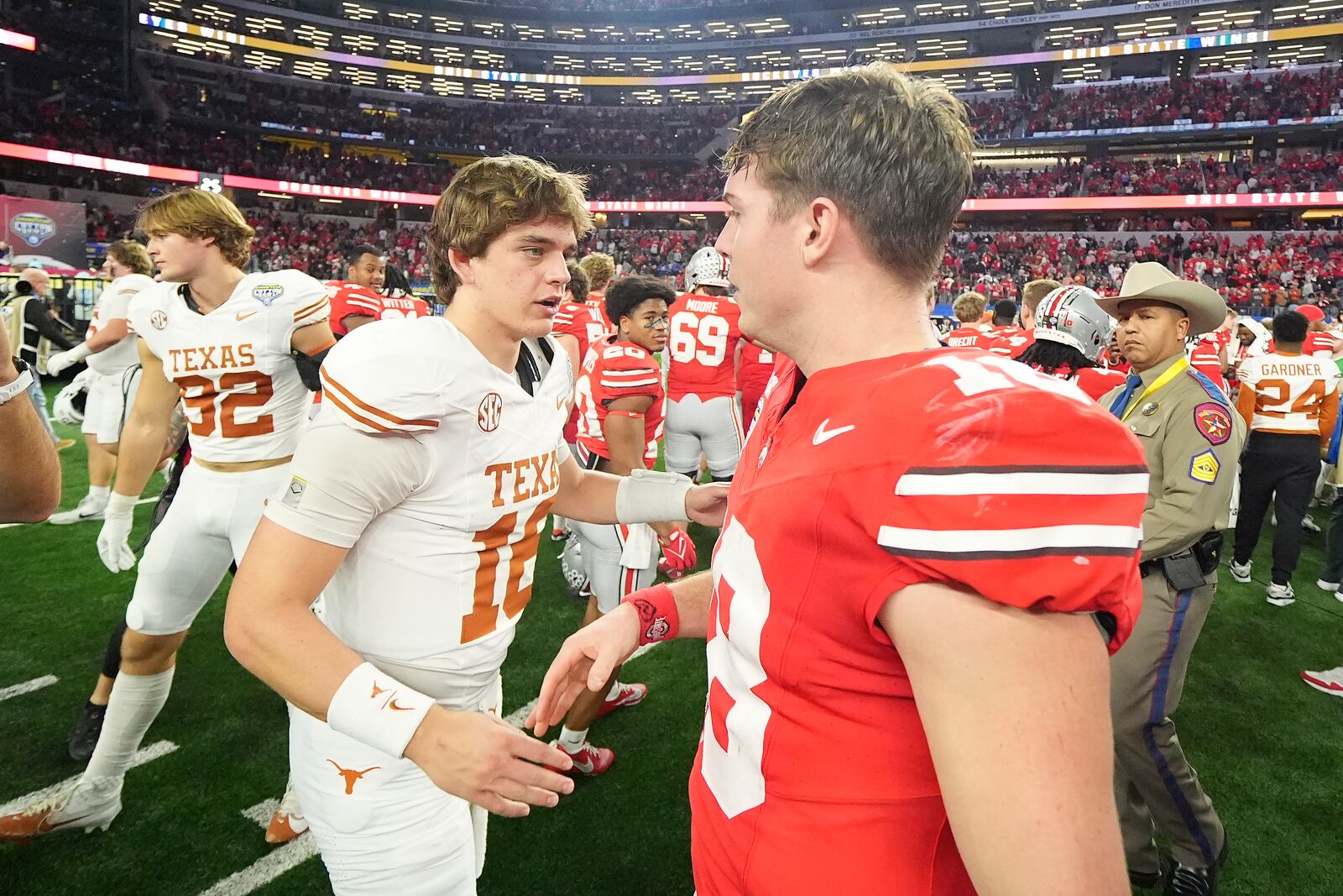 Texas quarterback Arch Manning, middle left, shakes hands with Ohio State quarterback Will Howard after the Cotton Bowl College Football Playoff semifinal game, Friday, Jan. 10, 2025, in Arlington, Texas. (AP Photo/Julio Cortez)