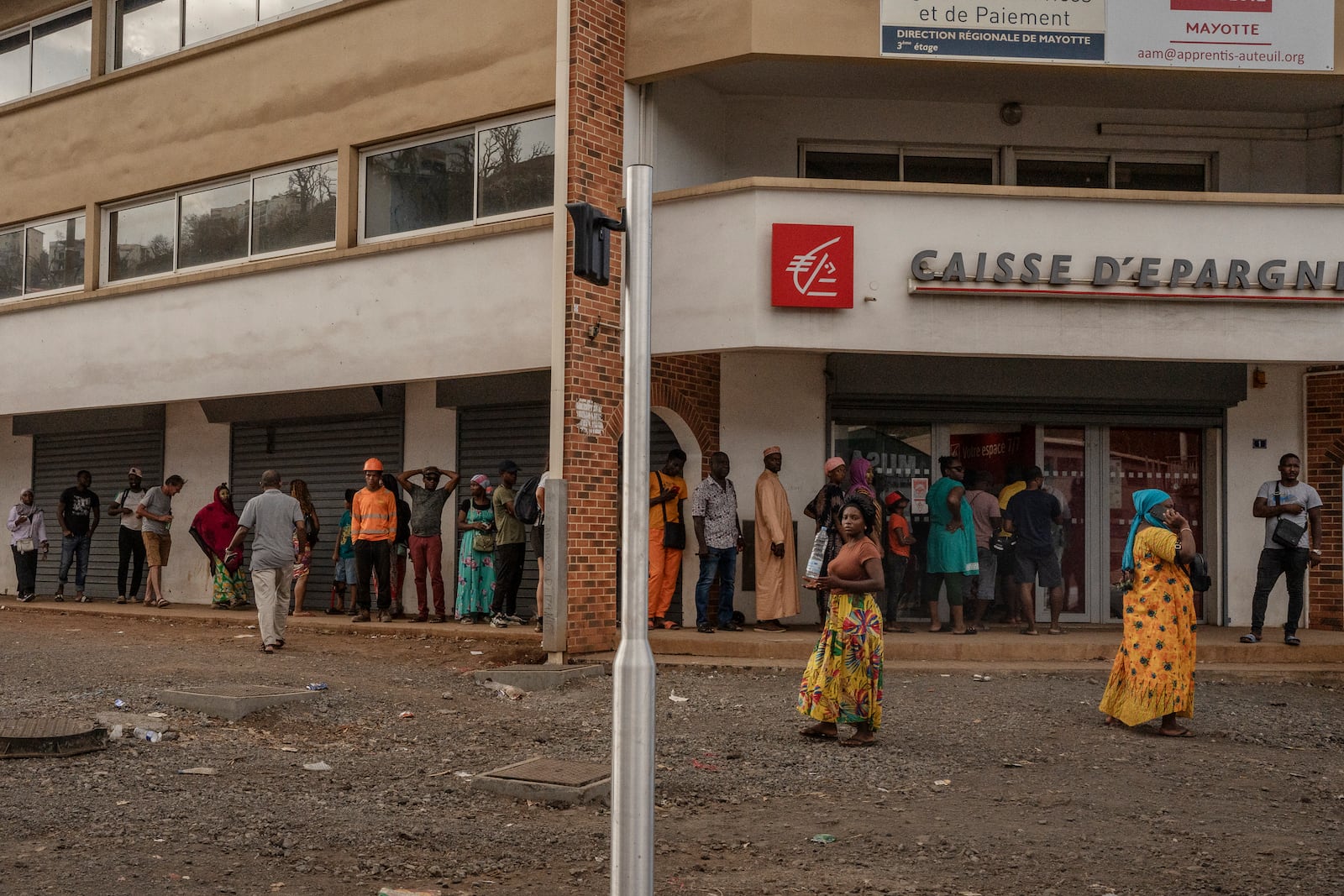 People wait in line to get cash, in Mamoudzou, Mayotte, Friday, Dec. 20, 2024. (AP Photo/Adrienne Surprenant)