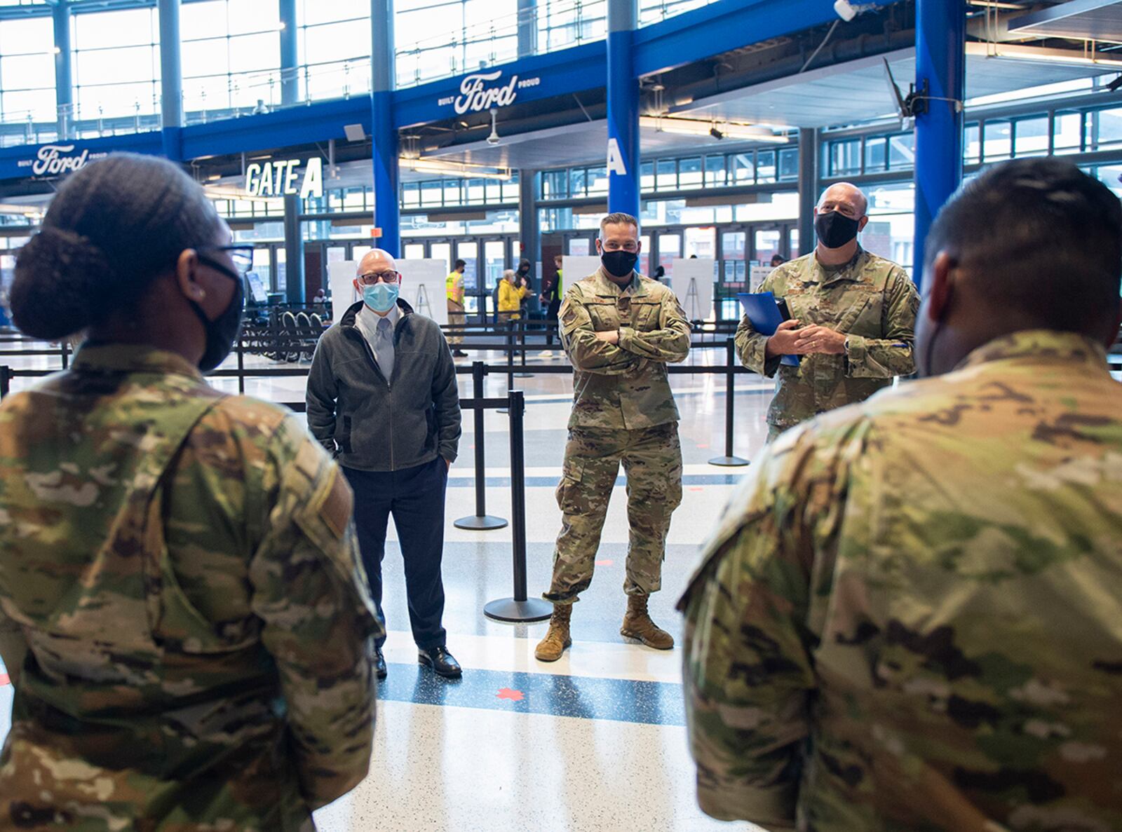 From left: Gregory Leingang, 88th Air Base Wing vice director; Col. Christian Lyons, 88th Medical Group commander; and Col. Patrick Miller, 88 ABW and installation commander, talk with 88th Medical Group Airmen from Wright-Patterson Air Force Base who are working in the community vaccination center’s registration area on May 3 at Ford Field in Detroit. U.S. AIR FORCE PHOTO/WESLEY FARNSWORTH