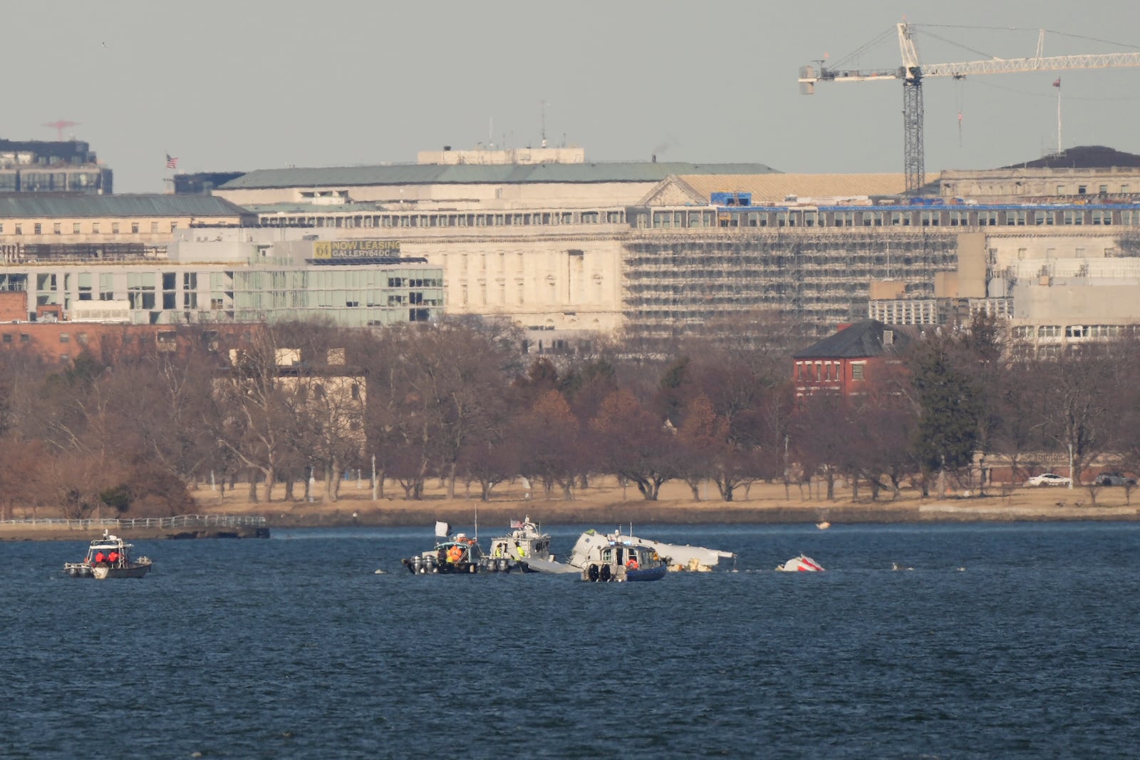 Search and rescue boats work on the Potomac river, Saturday, Feb. 1, 2025, in Arlington, Va., near the wreckage of an American Airlines jet that collided with a Black Hawk helicopter, as seen from Alexandria, Va. (AP Photo/Carolyn Kaster)