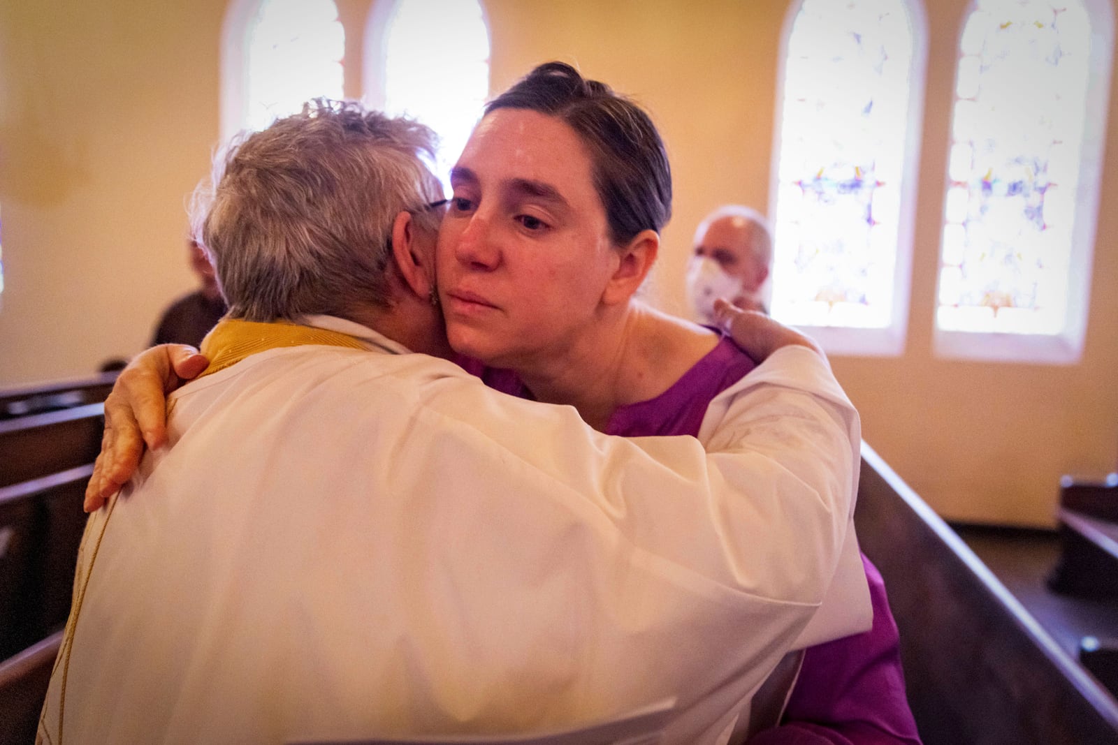 A congregant is hugged by a priest during a religious service in the aftermath of the Eaton Fire at Trinity Lutheran Church Sunday, Jan. 12, 2025 in Pasadena, Calif. (AP Photo/Ethan Swope)