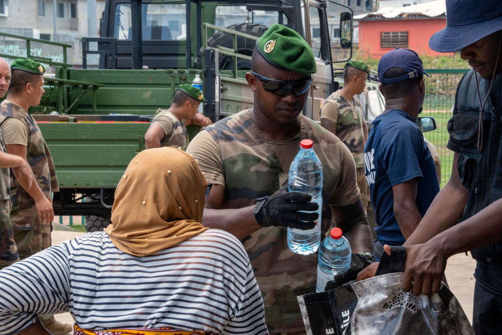 This photo provided by the French Army shows a soldier giving a bottle of water to a resident in the Indian Ocean French territory of Mayotte, Wednesday Dec.18, 2024, as the cyclone on Saturday was the deadliest storm to strike the territory in nearly a century. (D Piatacrrea, Etat Major des Armees/Legion Etrangere via AP)