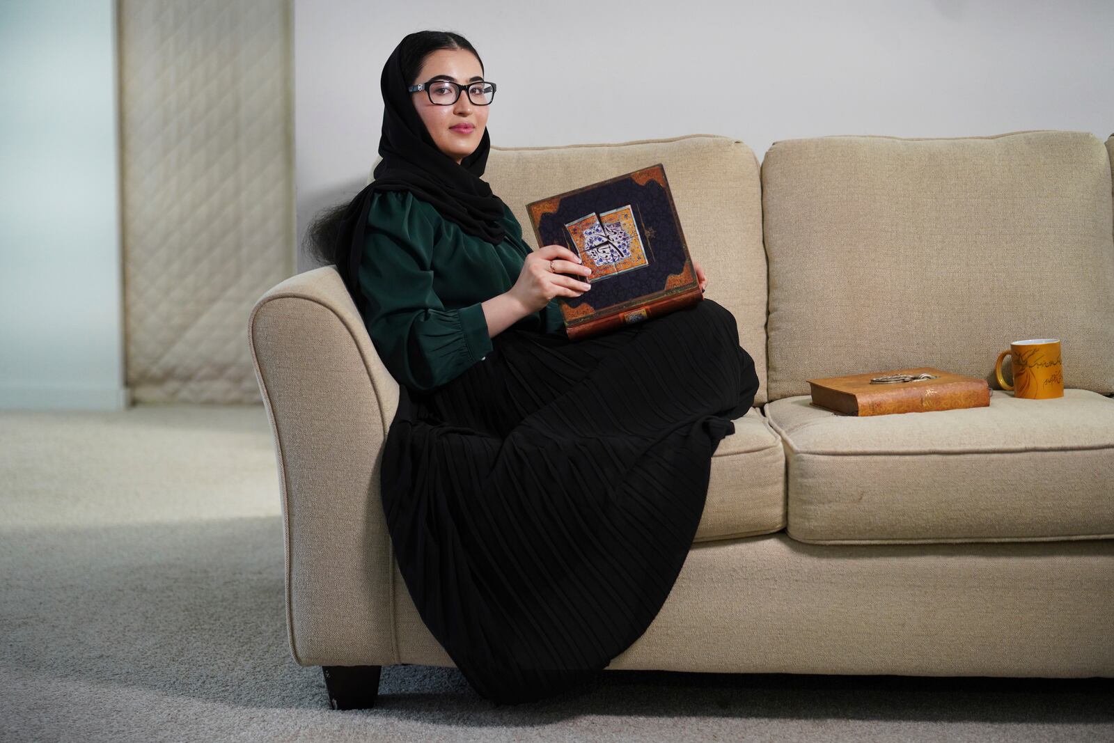 Marjila Badakhsh sits beside sentimental items, including a book of poems, brought with her from Afghanistan, Wednesday, March 5, 2025, in Alexandria, Va. (AP Photo/Jessie Wardarski)