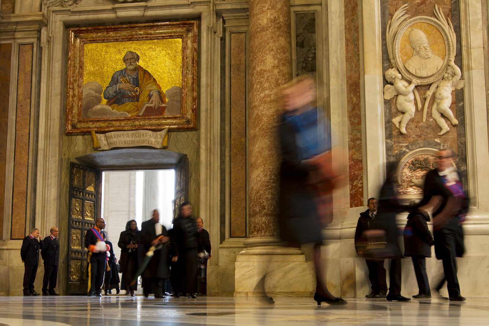 FILE - In this photo taken with a slow shutter speed, people walk through the Holy Door of St. Peter's Basilica, at the Vatican, Tuesday, Dec. 8, 2015. (AP Photo/Andrew Medichini, File)