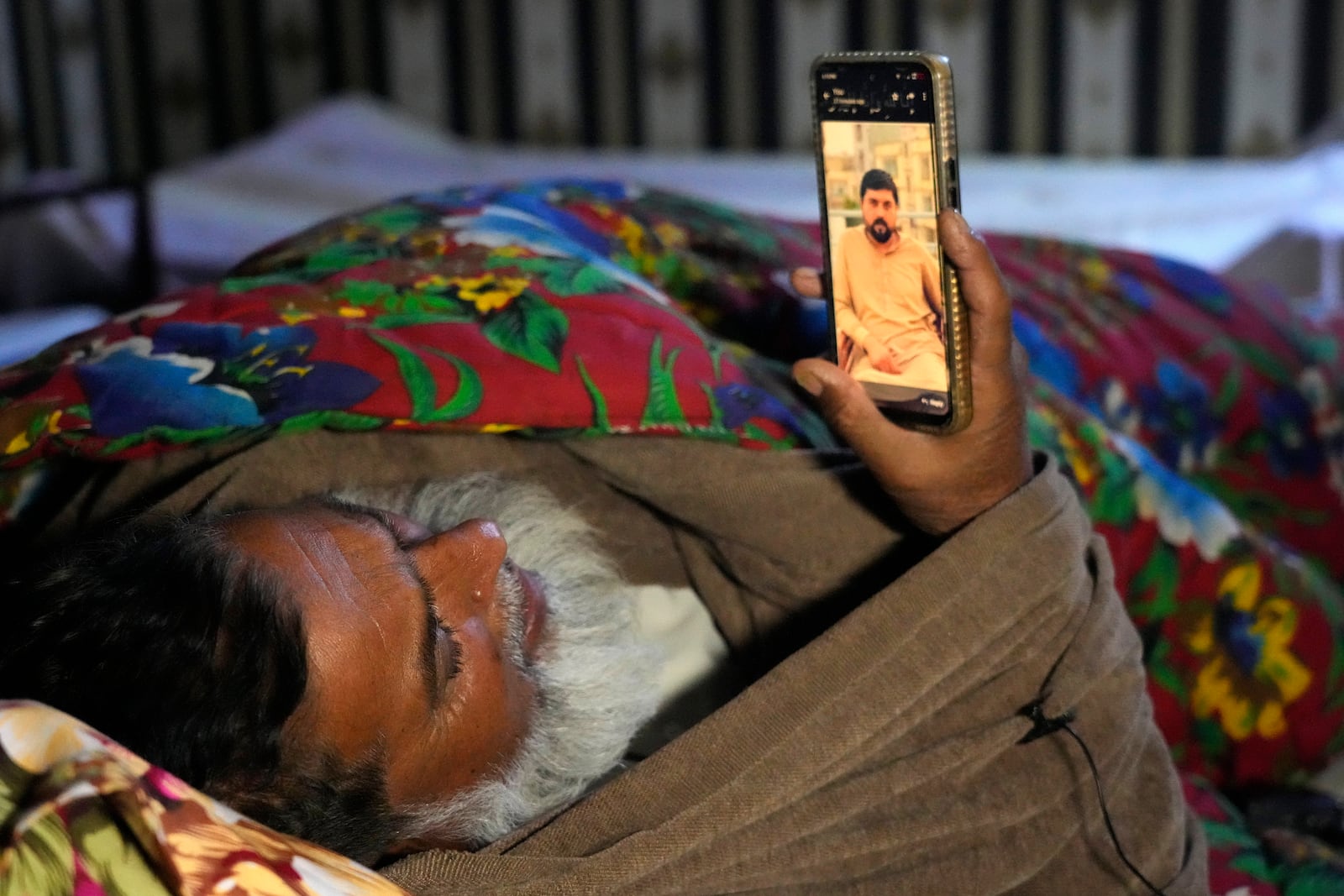 Shaukat Ali shows a picture of his son Atif Shahzad, one of the victims of a migrant boat that capsized in West Africa's Atlantic coastline, on his cell phone at his home, in Jura village, in the Lalamusa district in Pakistan, Friday, Jan. 17, 2024. (AP Photo/K.M. Chaudary)