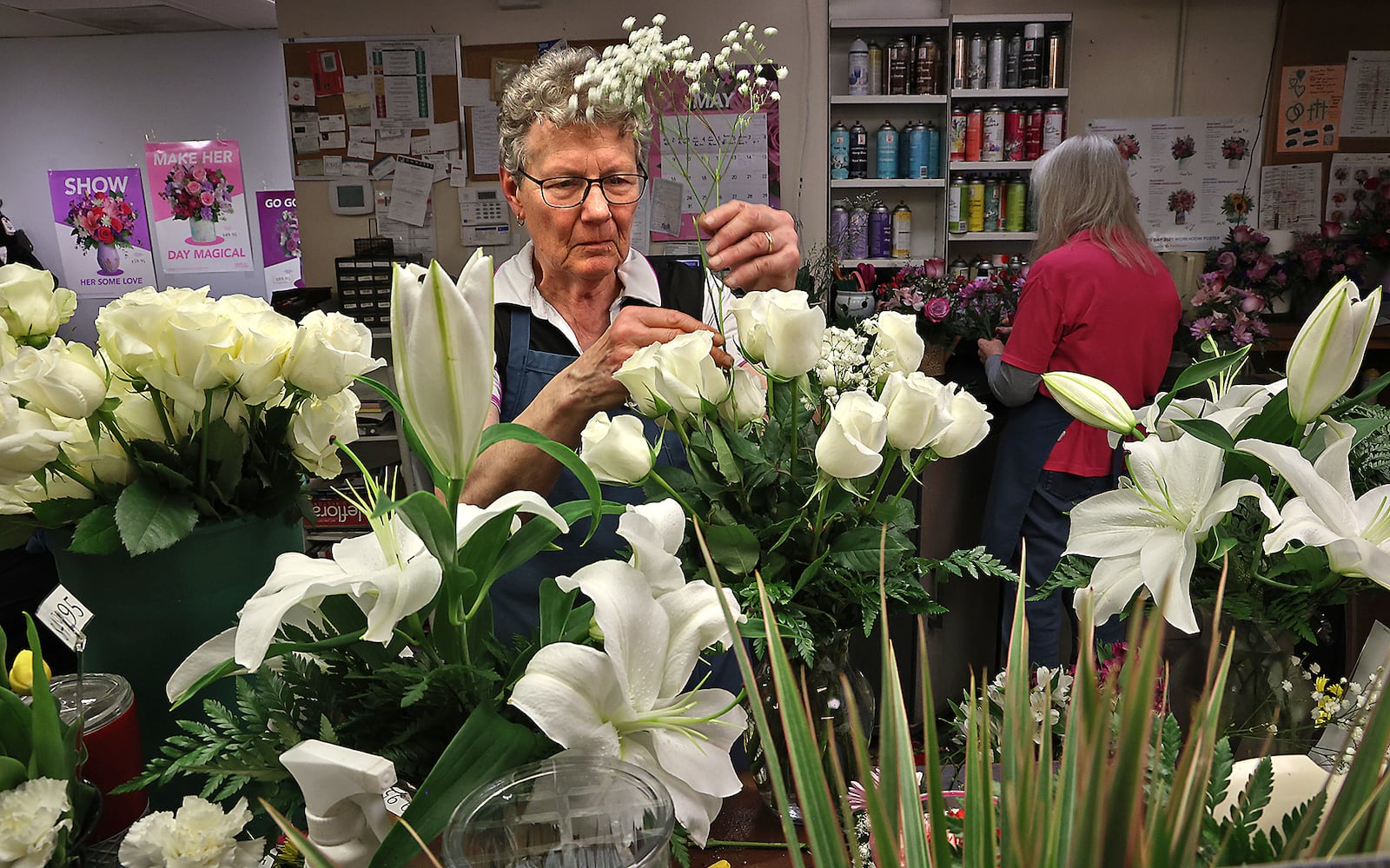 Kathy Ardle, the owner of Schneider's Florist, makes an arrangement of white roses for a customer Thursday. BILL LACKEY/STAFF