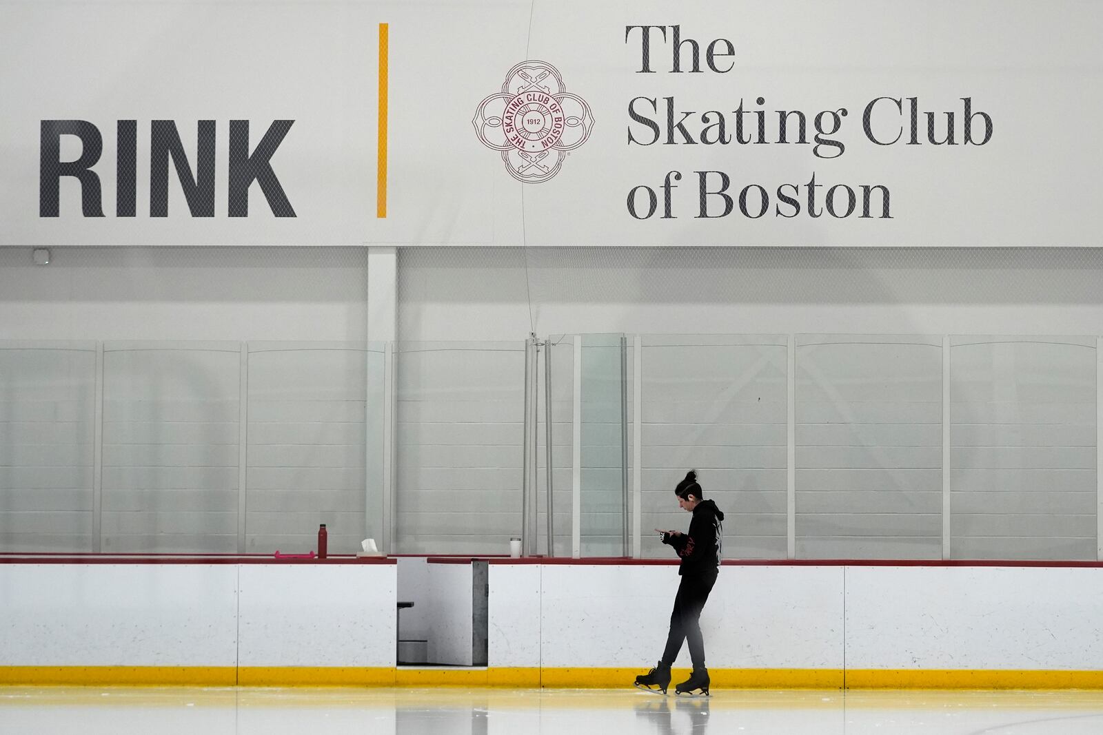 A skater checks her phone at The Skating Club of Boston, Thursday, Jan. 30, 2025, in Norwood, Mass. (AP Photo/Robert F. Bukaty)