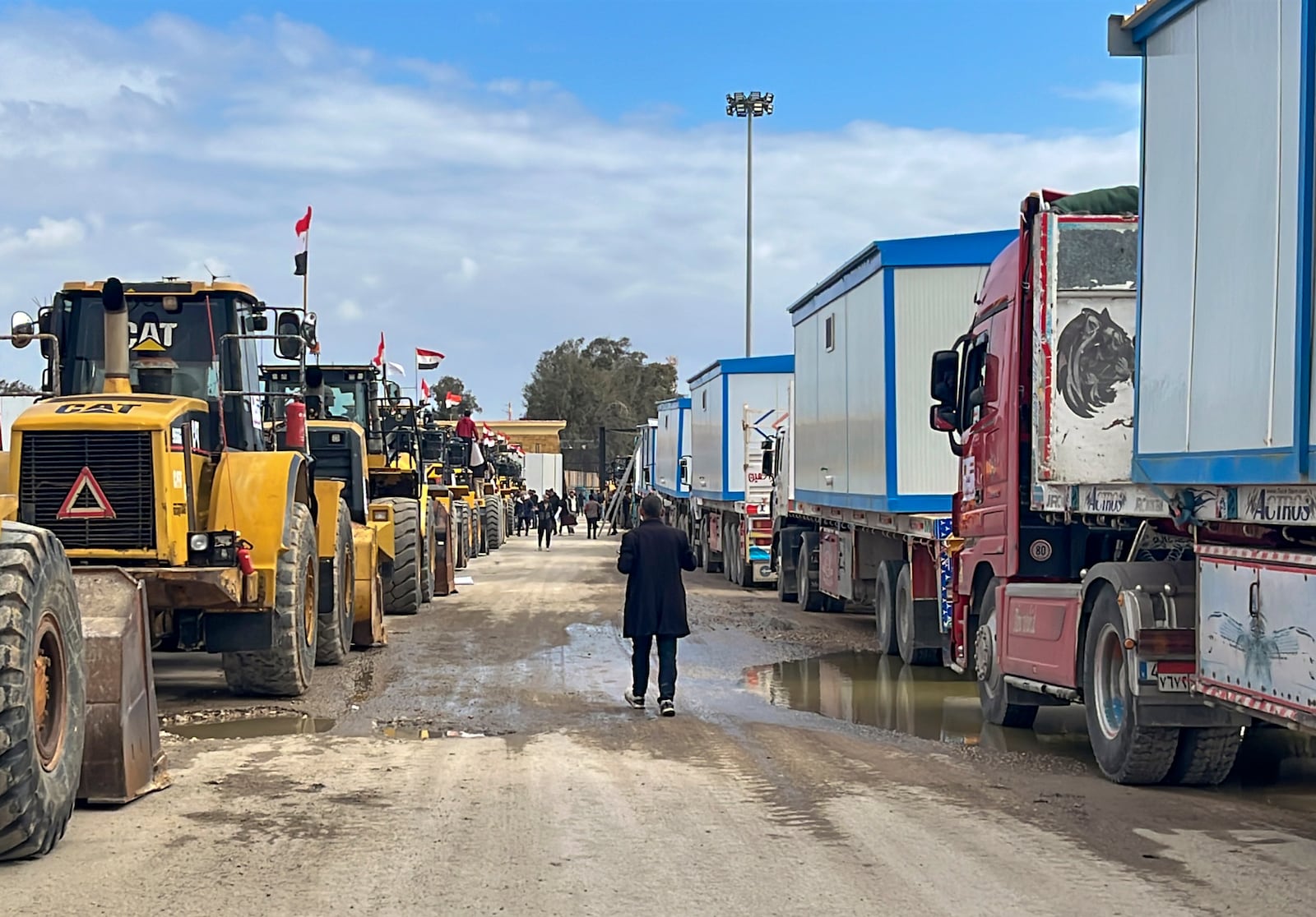 Bulldozers and trucks carrying caravans wait to enter Gaza at the Rafah border crossing between Egypt and the Gaza Strip, Thursday, Feb. 13, 2025. (AP Photo/Mohamed Arafat)