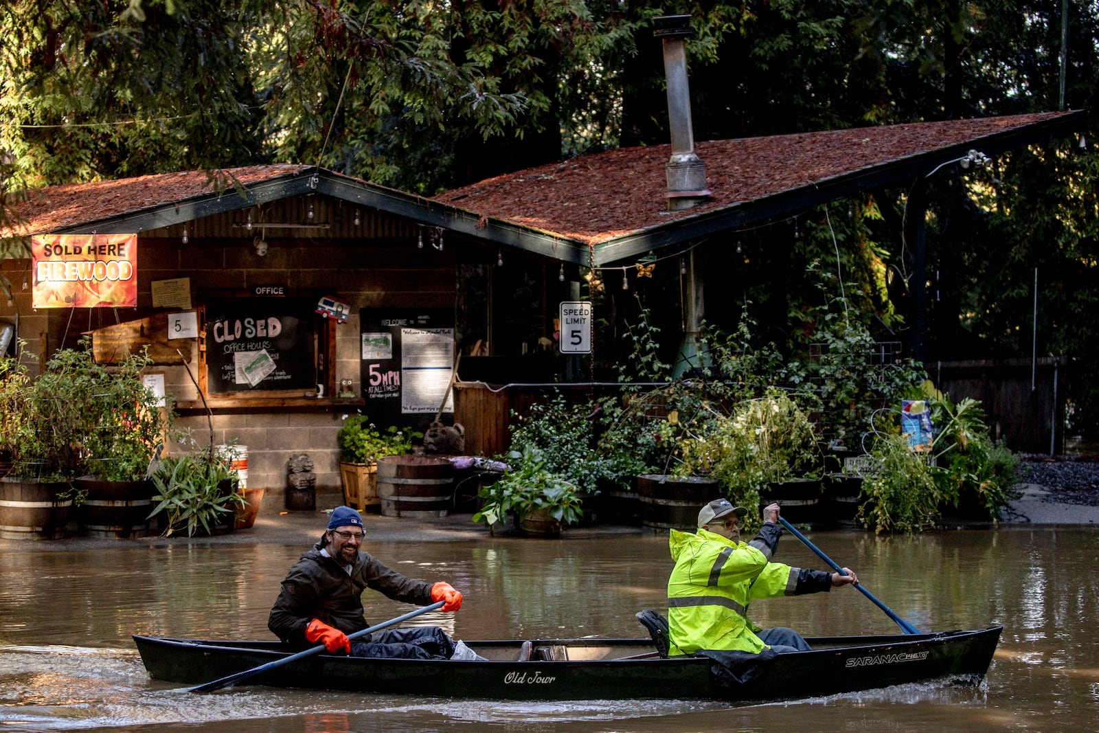 Kevin Ozorkiewicz, left, and neighbor John Phillips row a canoe at the flooded Mirabel RV Park & Campground after a major storm in Forestville, Calif., Sonoma County, Saturday, Nov. 23, 2024. (Stephen Lam/San Francisco Chronicle via AP)