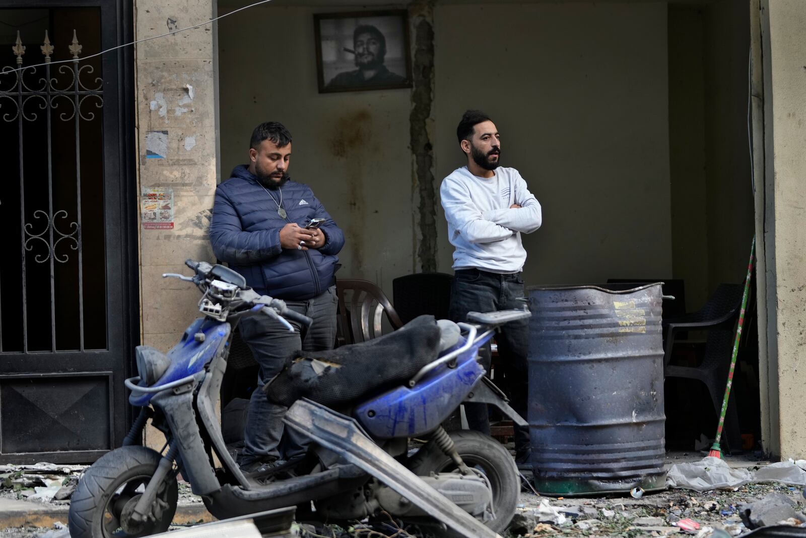 Lebanese men stand outside their damaged shop, as one of them looks at the destroyed building that was hit Sunday evening in an Israeli airstrike in Dahiyieh, in the southern suburb of Beirut, Lebanon, Monday, Nov. 25, 2024. (AP Photo/Hussein Malla)