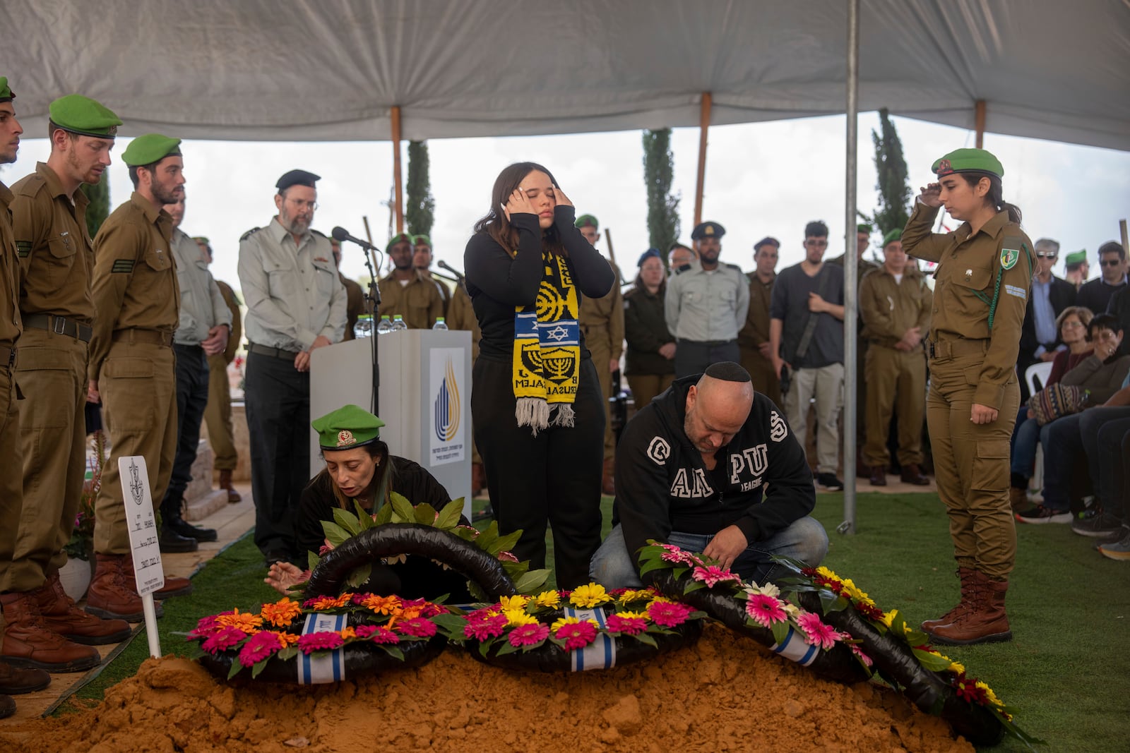 Gali and Nir, the parents of the Israeli soldier Sergeant Yahav Maayan who was killed in combat in the Gaza Strip, react next to his grave during his funeral at a military cemetery in Modiin, Israel, Sunday, Jan. 12, 2025. (AP Photo/Ohad Zwigenberg)