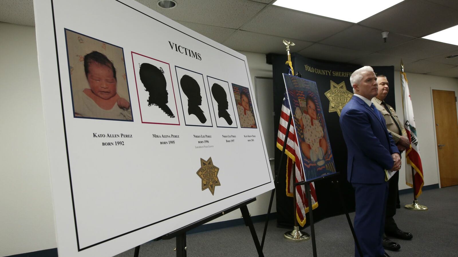 A poster of five infants believed to be killed by their father, Paul Allen Perez, is displayed during a news conference attended by Yolo County District Attorney Jeff Reisig, left, and Sheriff Tom Lopez, right, in Woodland, Calif., Monday, Jan. 27, 2020. Perez, 57, is accused of killing the children over a nine-year span between 1992 and 2001.