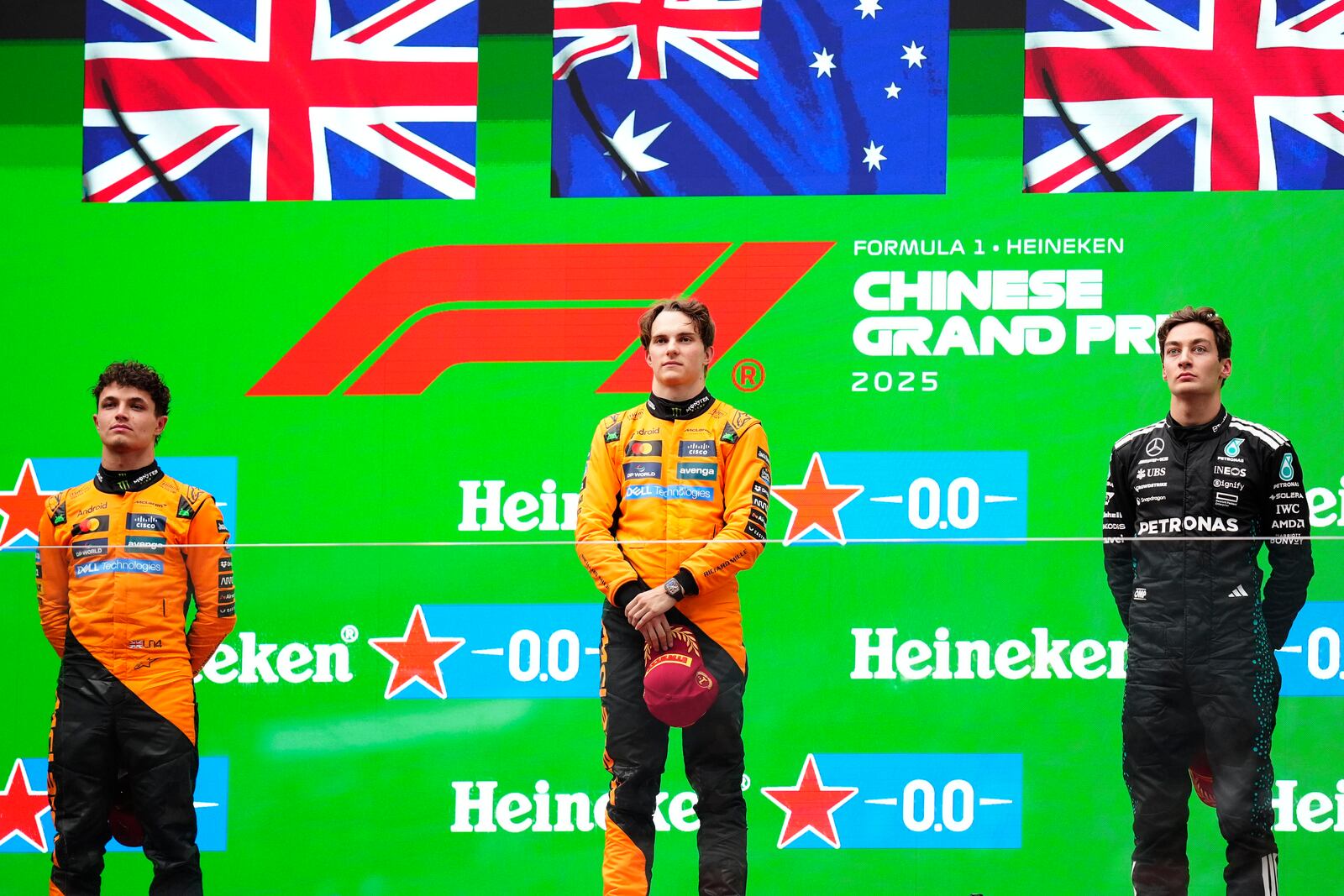 McLaren driver Oscar Piastri of Australia, centre, is flanked on the podium with McLaren driver Lando Norris of Britain, left, and Mercedes driver George Russell of Britain after winning the Chinese Formula One Grand Prix race at the Shanghai International Circuit, Shanghai, Sunday, March 23, 2025. (AP Photo)