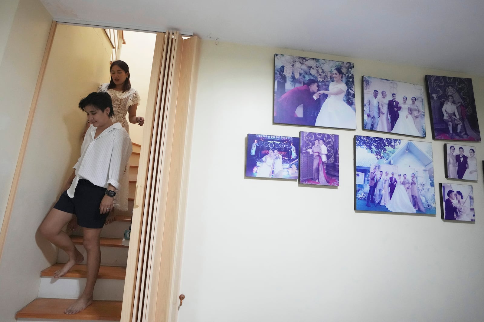 Danaya Phonphayung walks in front of her partner Sunma Piamboon next to their wedding photos at their home in Bangkok, Thailand, on Jan. 13, 2025. (AP Photo/Sakchai Lalit)