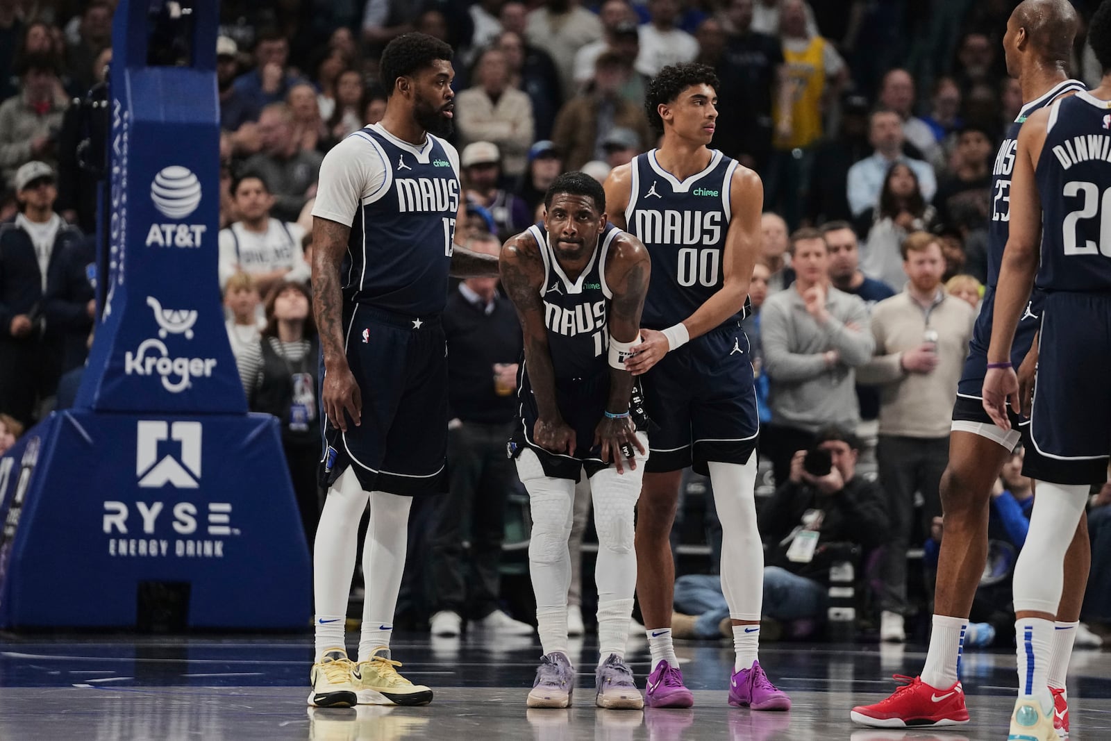 Dallas Mavericks' Naji Marshall, left, and Max Christie (00) stand by Kyrie Irving (11), center, after Irving shot free throws after suffering an injury in the first half of an NBA basketball game against the Sacramento Kings in Dallas, Monday, March 3, 2025. (AP Photo/Tony Gutierrez)