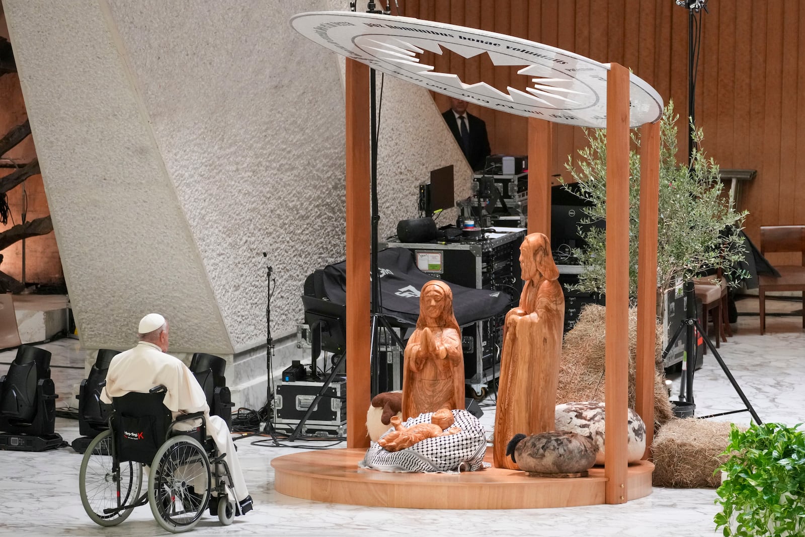 Pope Francis prays in front of a Nativity Scene crafted in the West Bank city of Bethlehem, as he arrives for a meeting with the donors of the fir tree set up in St. Peter's Square as a Christmas tree and those who have crafted the life-size nativity scene at the tree's feet, in the Paul VI hall at the Vatican, Saturday, Dec. 7, 2024. (AP Photo/Andrew Medichini)