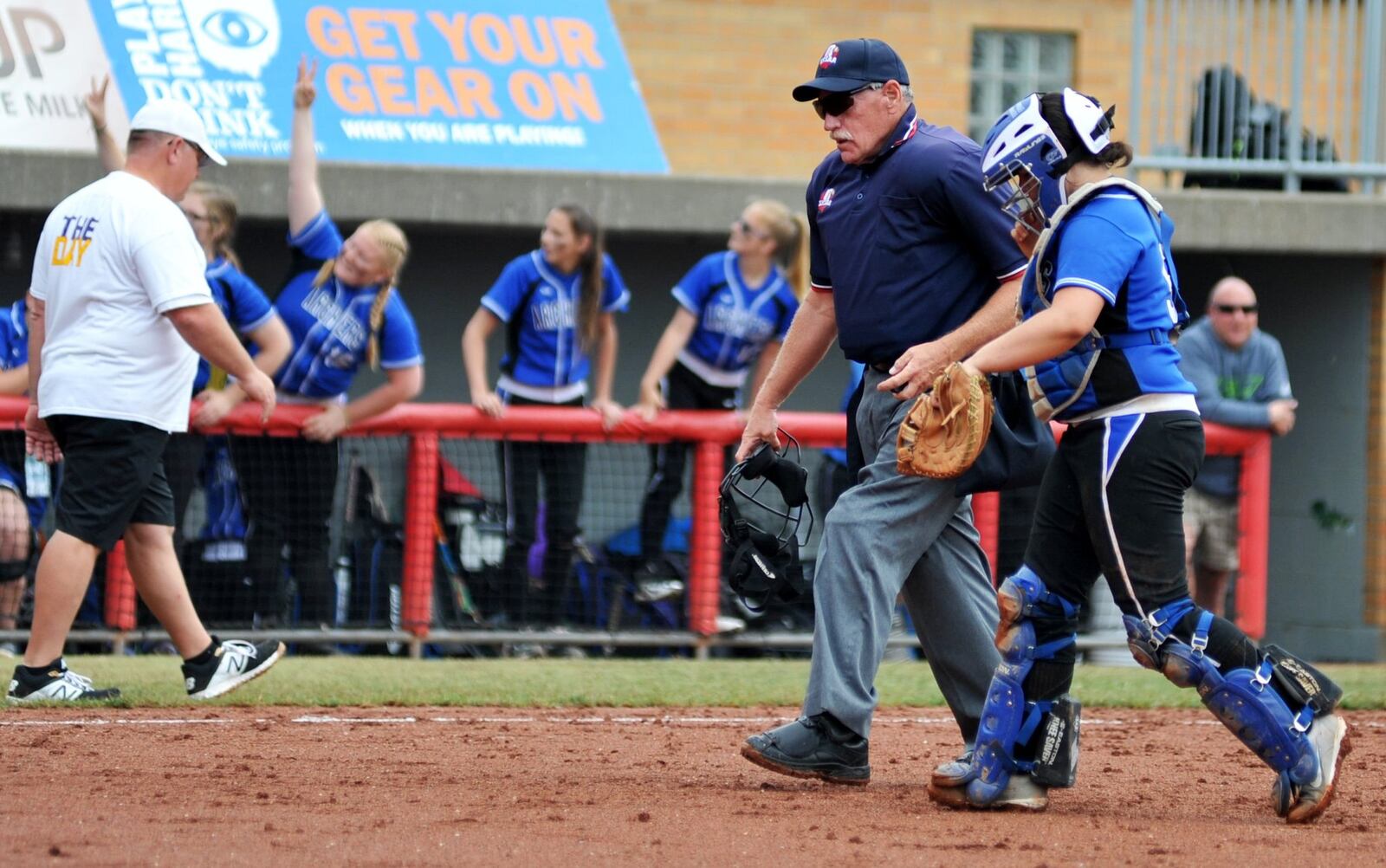 Home-plate umpire Tom Hathaway heads back toward the plate with Antwerp catcher Karsyn Brumett on Sunday during the Archers’ 5-0 win over Mechanicsburg in the Division IV state championship softball game at Firestone Stadium in Akron. RICK CASSANO/STAFF