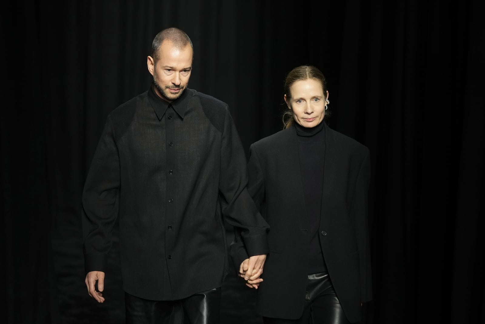 Designers Lucie e Luke Meier greet the audience at the end of the Jil Sander Fall/Winter 2025-2026 women's collection presented in Milan, Italy, Wednesday, Feb. 26, 2025. (AP Photo/Antonio Calanni)