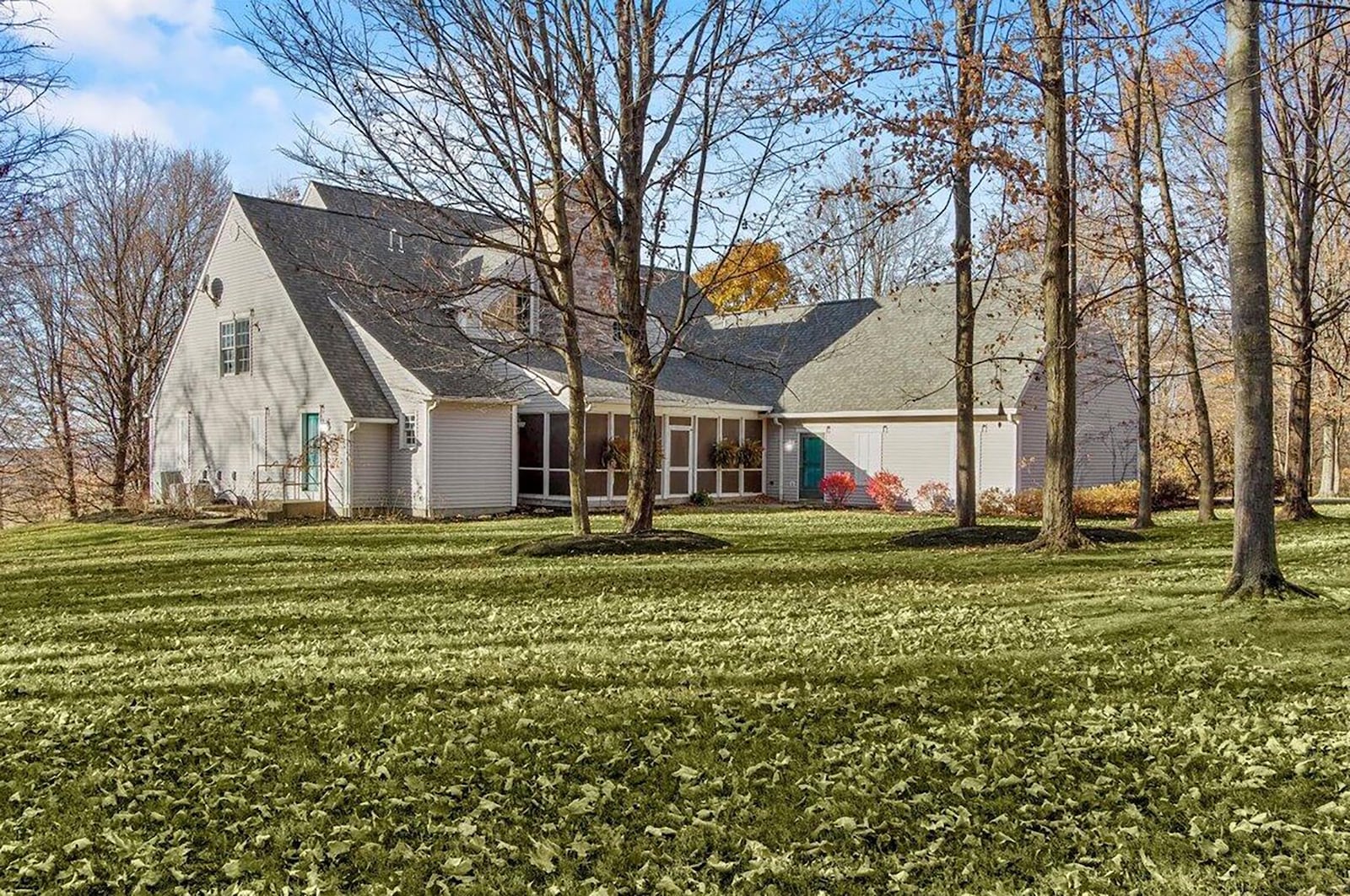 The rear of the home has a sunroom (fully screened) and a three-car attached, side-entry garage. The backyard is heavily wooded.