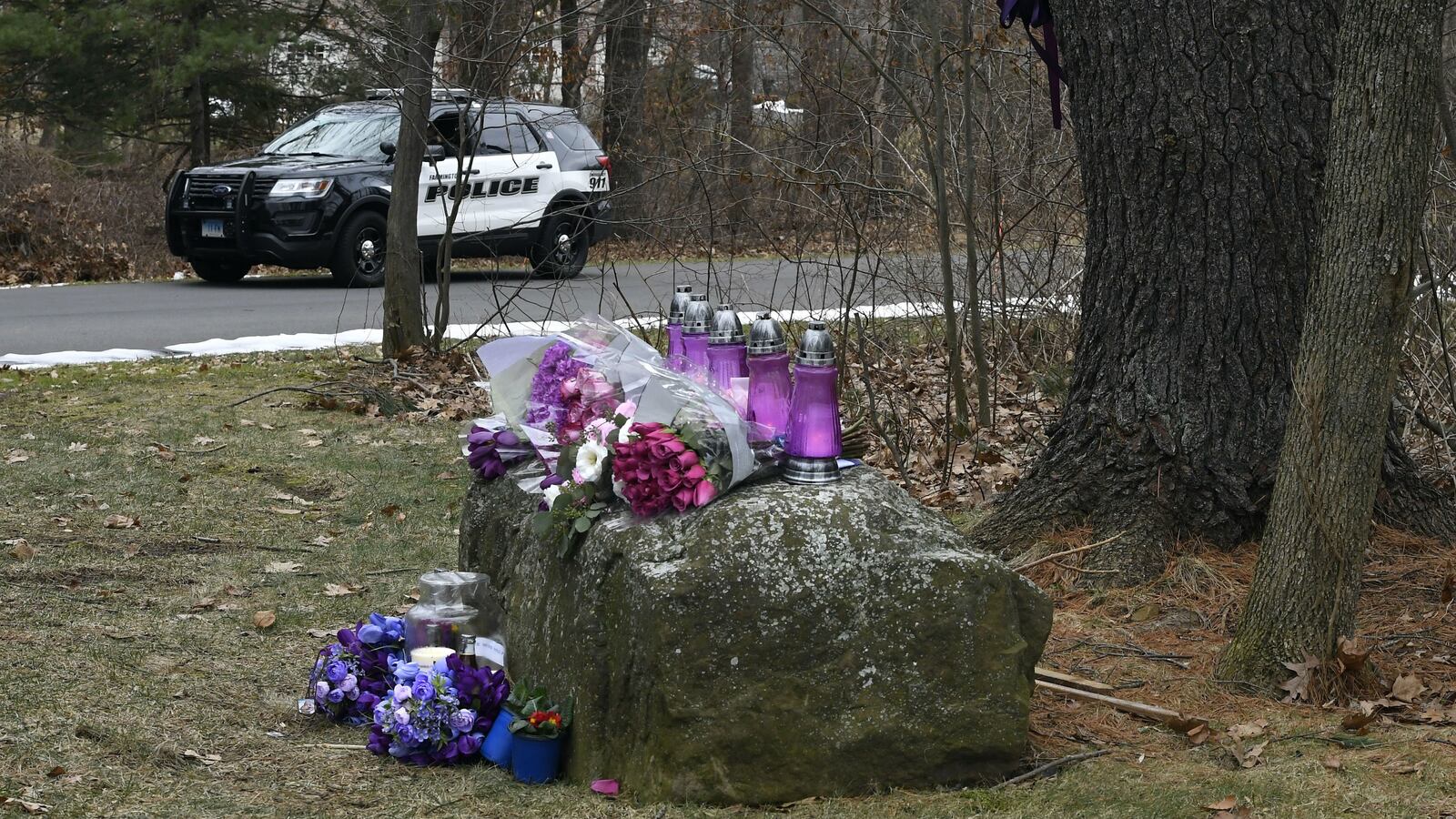 A police vehicle is seen near a memorial for Jennifer Dulos near her estranged husband's Farmington, Conn., home. Fotis Dulos, 52, is accused of murder and conspiracy in Jennifer Dulos' May 2019 disappearance. He attempted suicide at his home Tuesday, Jan. 28, 2020.