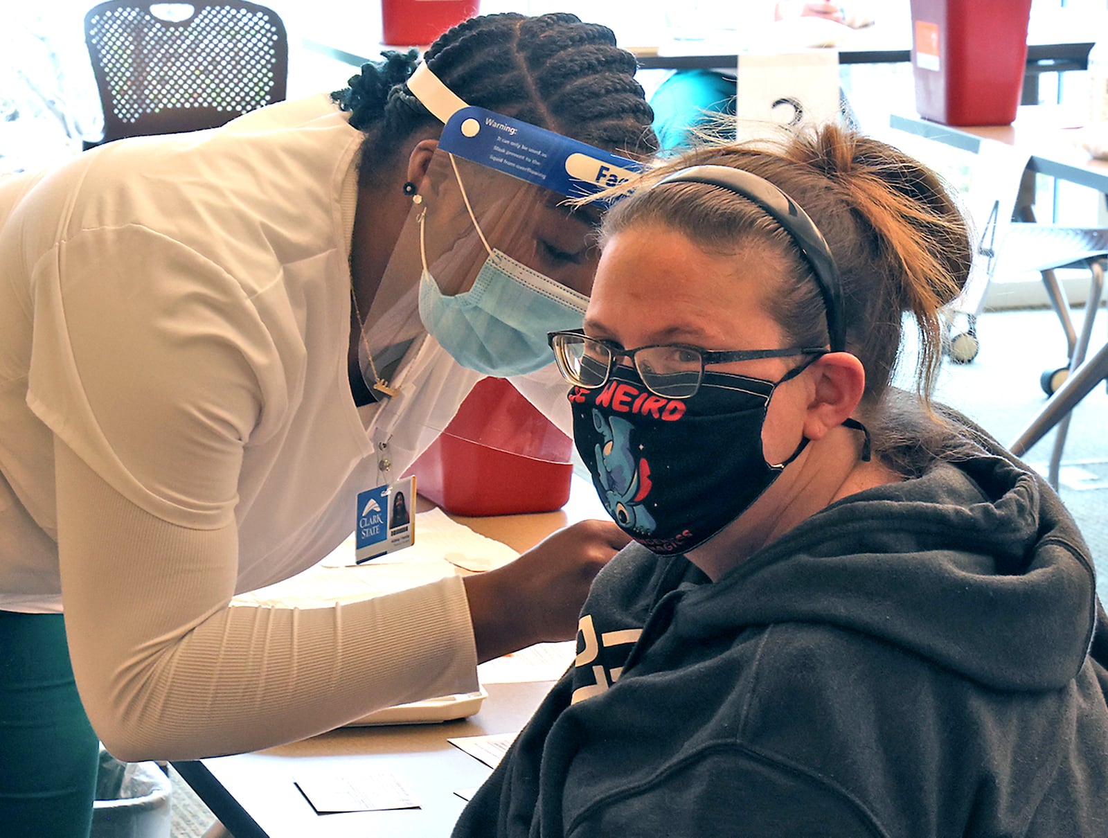 Adalay Yearby, a nursing student at Clark State College, gives Amanda Kothman a COVID vaccine injection in April at a clinic on the Leffel Lane campus. The college will return to regular operations starting June 1.  BILL LACKEY/STAFF