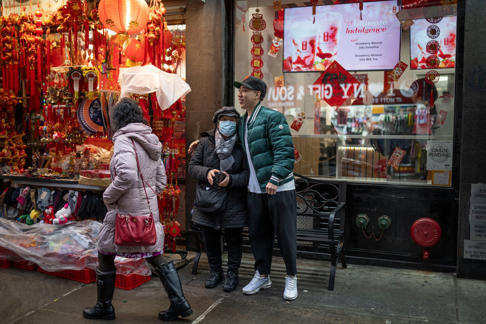 Karho Leung, 33, right, one of the founders of 12 Pell, a local barbershop, serendipitously happens upon his mother as she sits on a bench along Mott Street in Manhattan's Chinatown neighborhood, Thursday, Jan. 25, 2024, in New York. (AP Photo/John Minchillo)