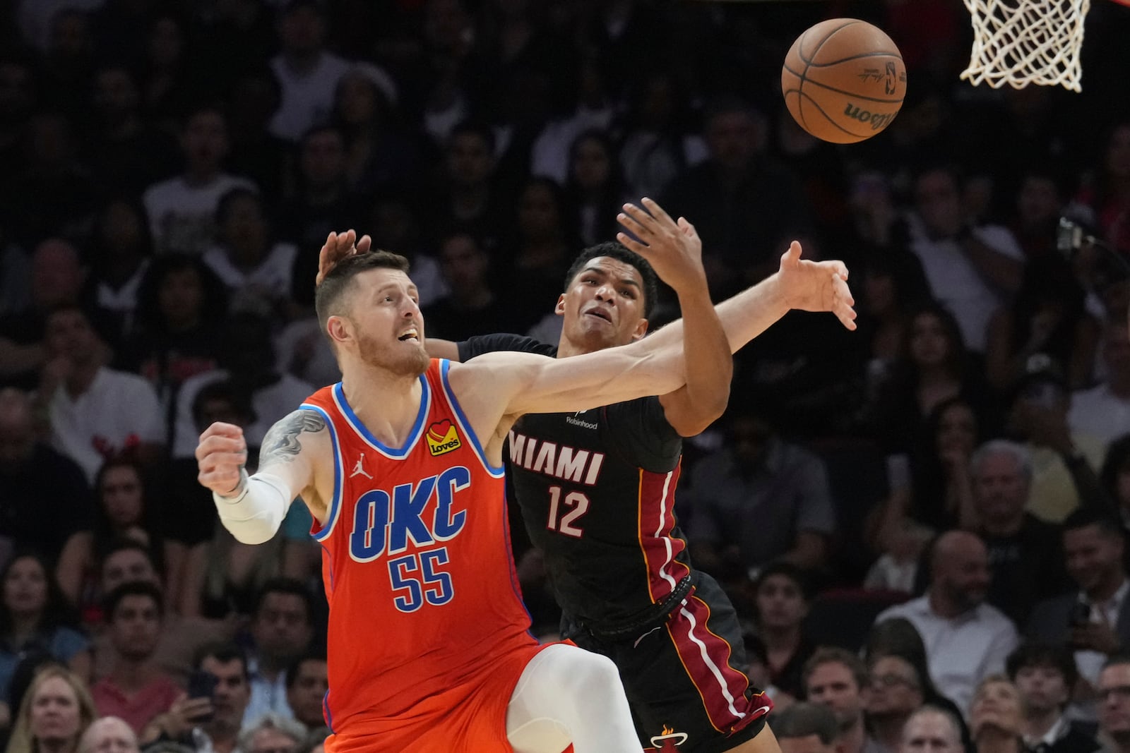 Oklahoma City Thunder center Isaiah Hartenstein (55) slaps the ball away from Miami Heat guard Dru Smith (12) during the second half of an NBA basketball game, Friday, Dec. 20, 2024, in Miami. (AP Photo/Marta Lavandier)