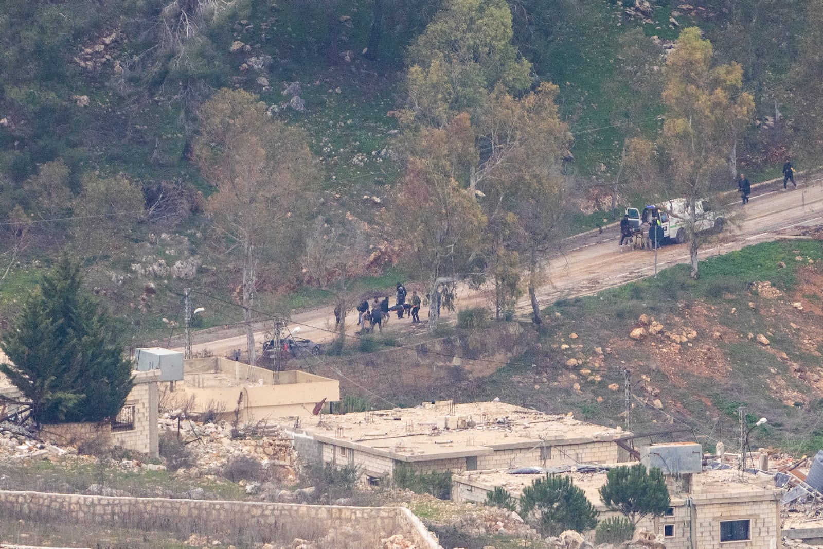 "Lebanese emergency services evacuate people that were wounded by gunshots as they approached the outskirts of the village of Al-Aadaissah in southern Lebanon, where Israeli soldiers continue to operate despite the ceasefire, as seen from northern Israel, Sunday, Jan. 26, 2025. (AP Photo/Ariel Schalit)