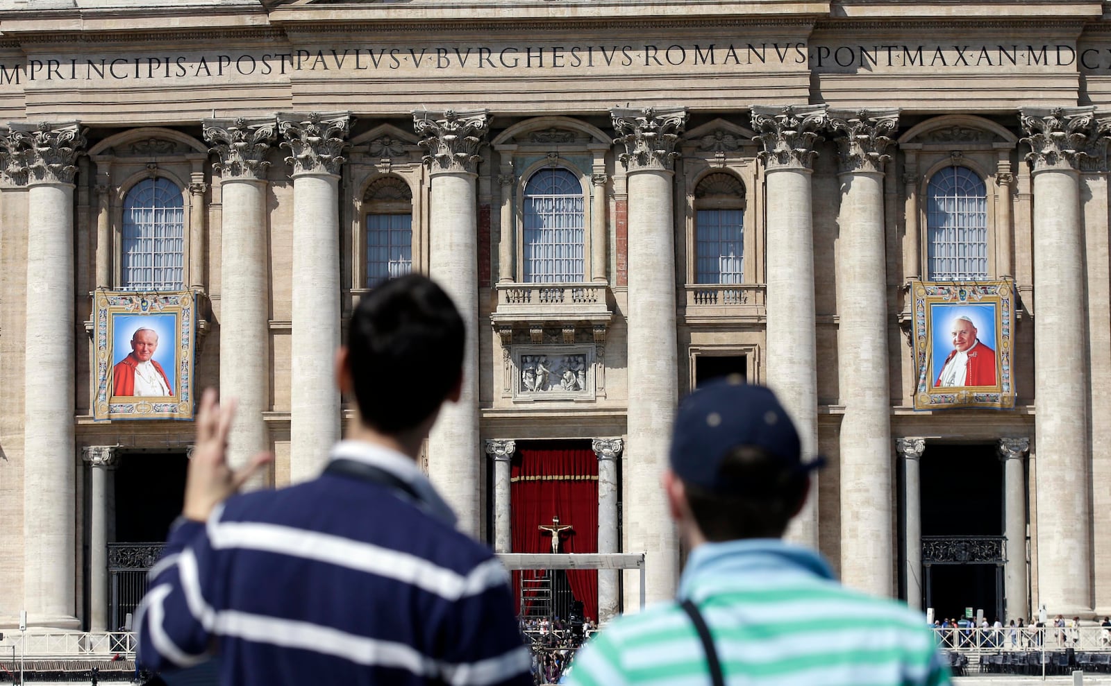 FILE-- The tapestries showing late Pope John Paul II, left, and Pope John XXIII hang from the facade of St. Peter's Basilica as faithful and pilgrims crowd St. Peter's Square at the Vatican, Friday, April 25, 2014. (AP Photo/Gregorio Borgia)