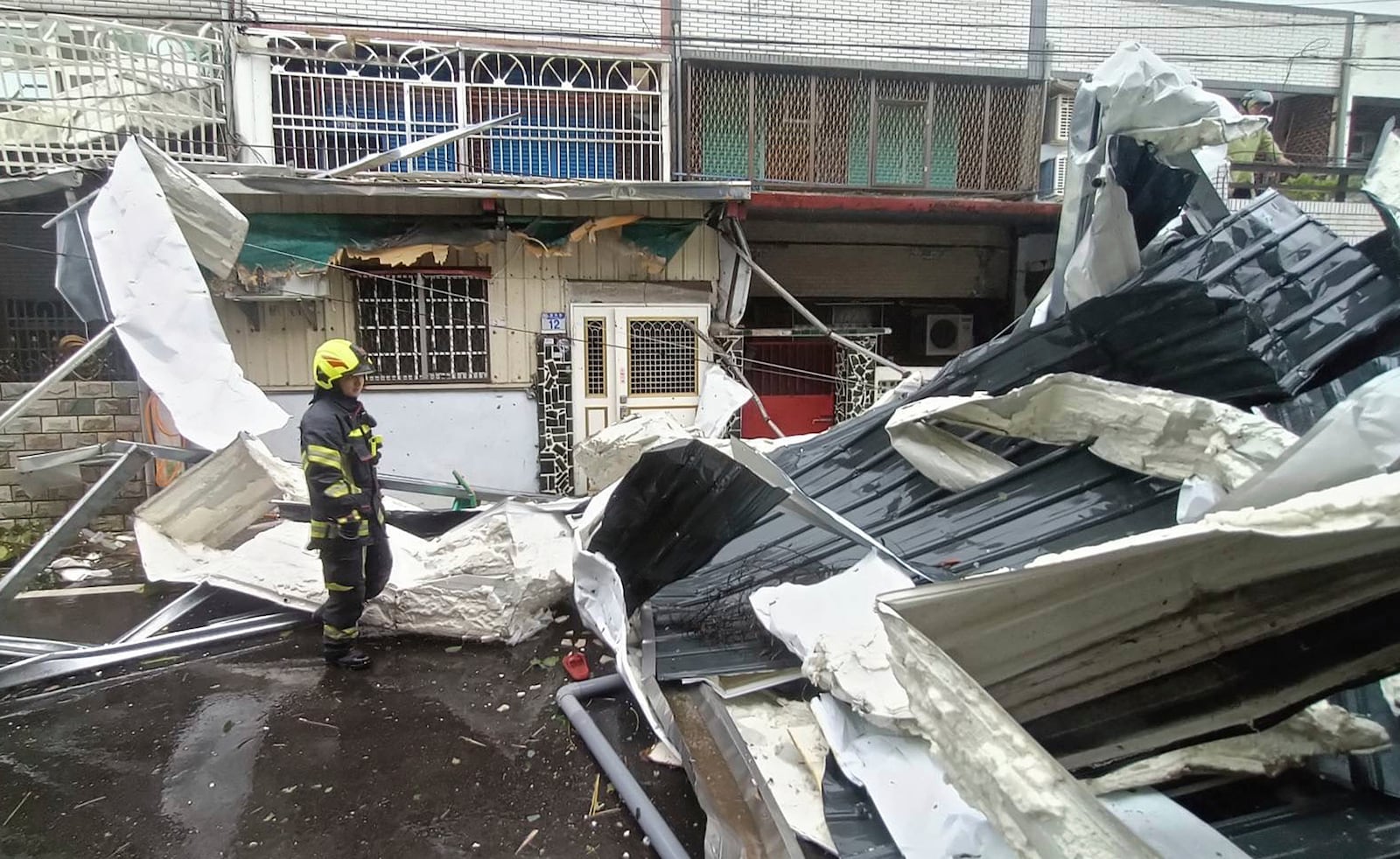 In this photo released by Hualien County Fire Department, police check a blown roof destroyed by the wind of Typhoon Kong-rey in Hualien County, eastern Taiwan, Thursday, Oct. 31, 2024. (Hualien County Fire Department via AP)