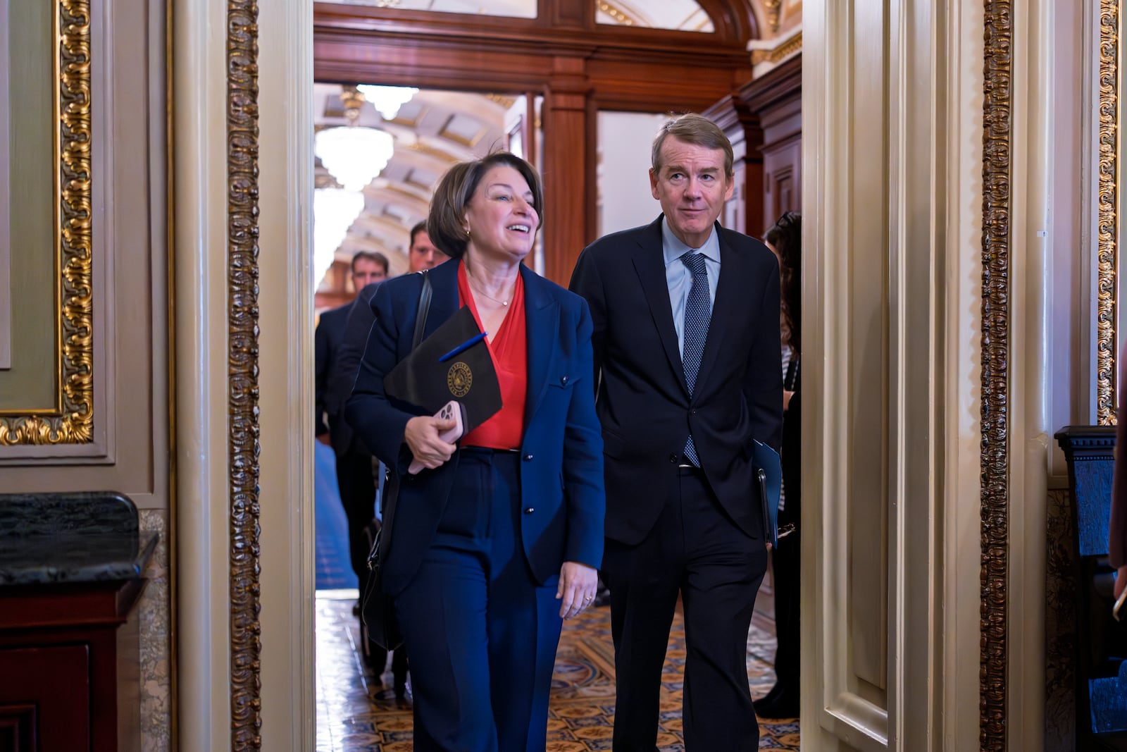 Sen. Amy Klobuchar, D-Minn.,, left, and Sen. Michael Bennet, D-Colo., arrive as Senate Democrats gather behind closed doors to mount a last-ditch protest over a Republican-led spending bill that already passed the House, at the Capitol in Washington, Thursday, March 13, 2025. (AP Photo/J. Scott Applewhite)