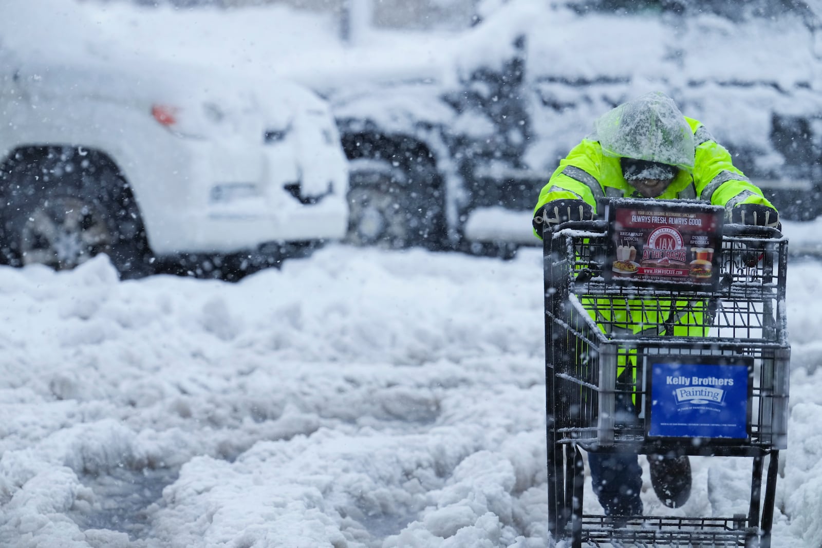 A person pushes a shopping cart on a snow-covered parking lot during a storm Thursday, Feb. 13, 2025, in Truckee, Calif. (AP Photo/Brooke Hess-Homeier)