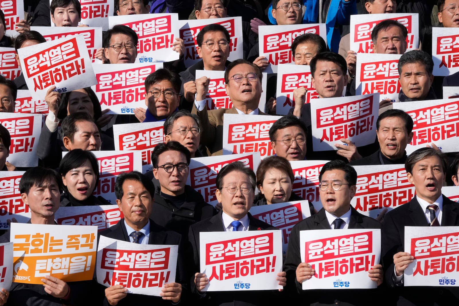 South Korea's main opposition Democratic Party leader Lee Jae-myung, bottom center, shout slogans during a rally against President Yoon Suk Yeol at the National Assembly in Seoul, South Korea, Wednesday, Dec. 4, 2024. The signs read "Yoon Suk Yeol should resign." (AP Photo/Ahn Young-joon)