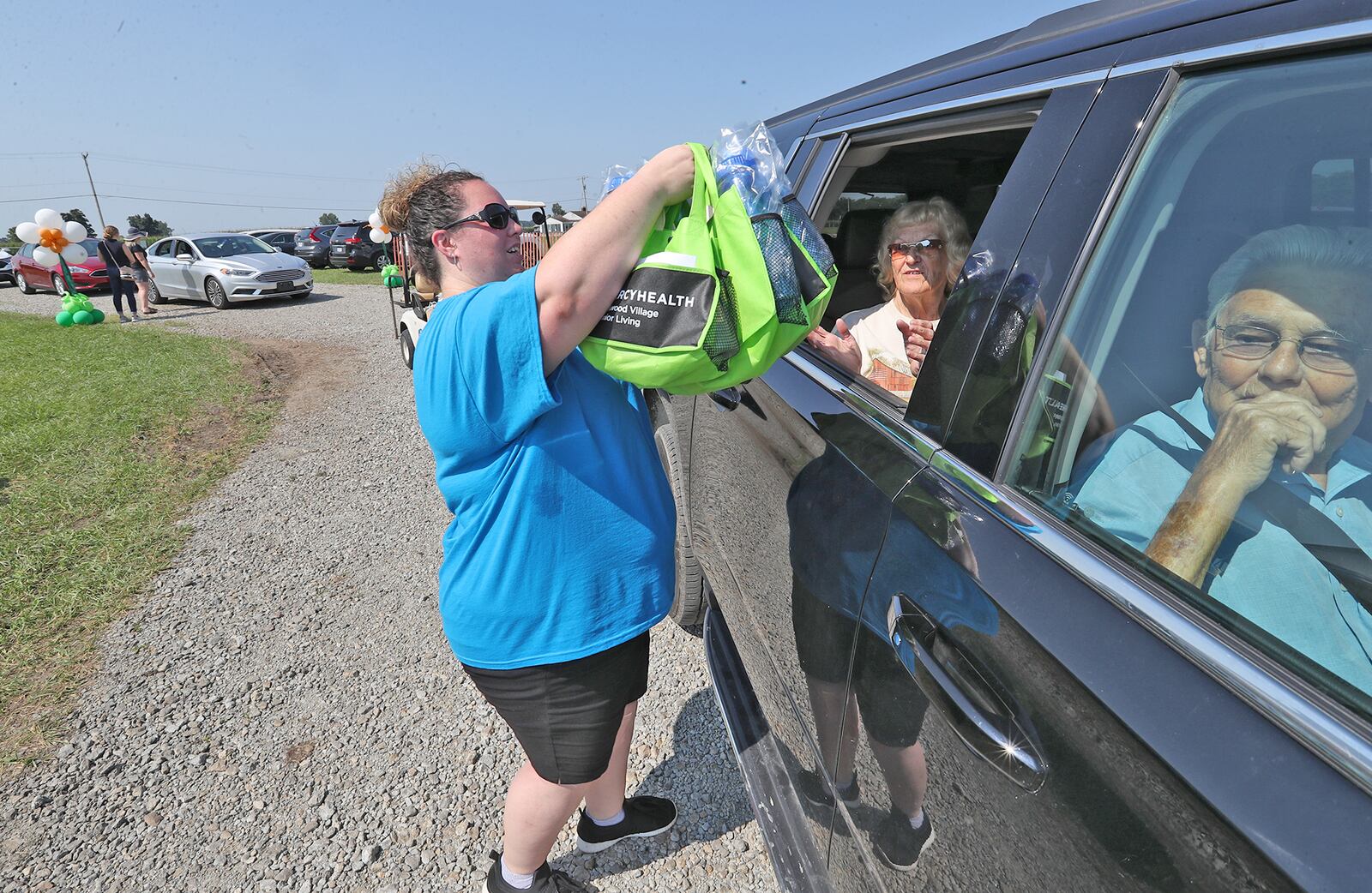 Teresa Blue-McWhorter, from Forest Glen Health Campus, hands a couple gift bags through the car window for a Golden Anniversary Couple Tuesday at the Clark County Fair. BILL LACKEY/STAFF