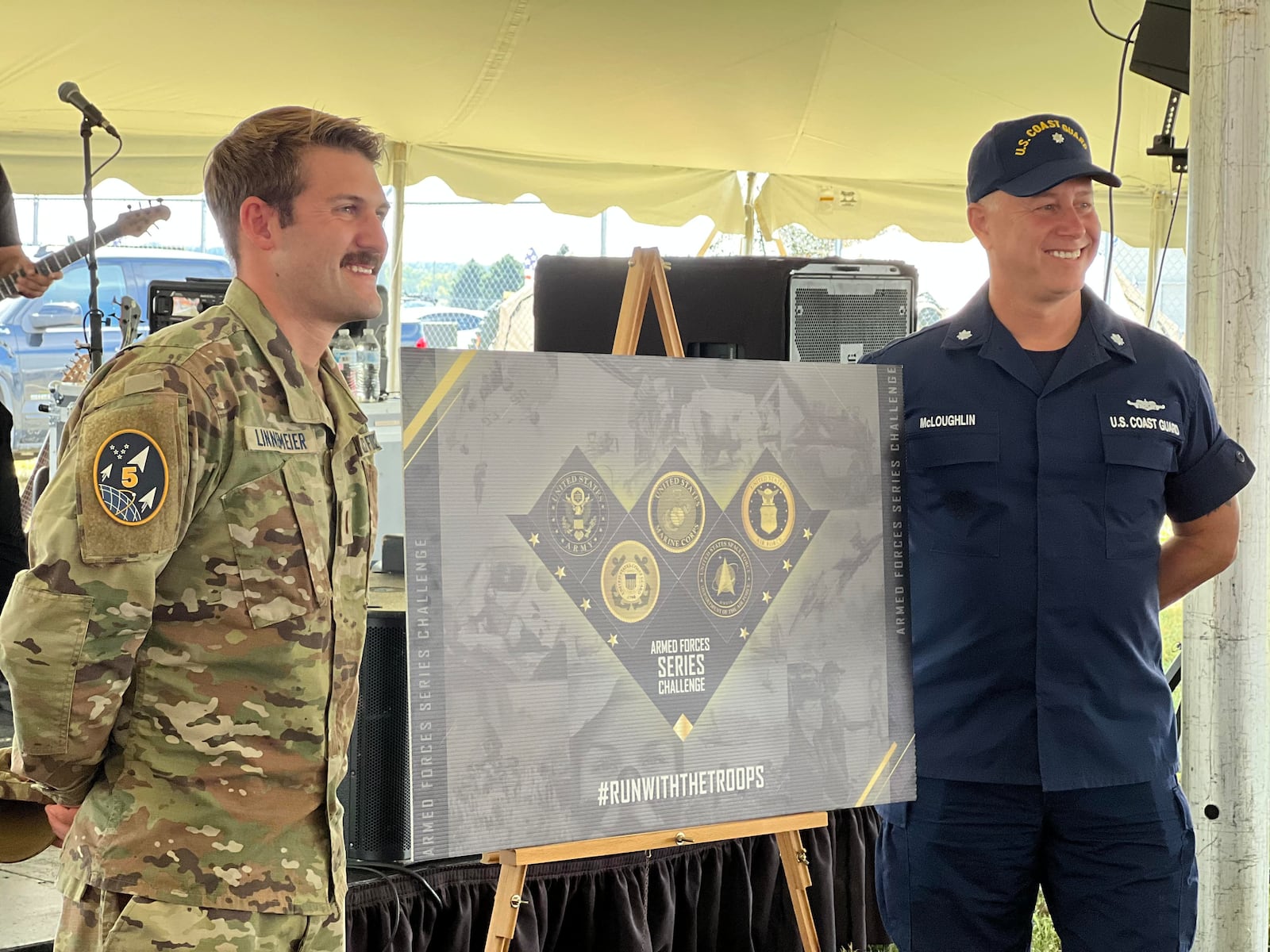 Lt. Russell Linnemeier of the U.S. Space Force, left, and Commander Dave McLaughlin of the U.S. Coast Guard, stand beside a visual of the Armed Forces Series Challenge medal. The emblem was designed by Bailey George, who is the Marine Corps Marathon graphics design and project lead. AIMEE HANCOCK/STAFF