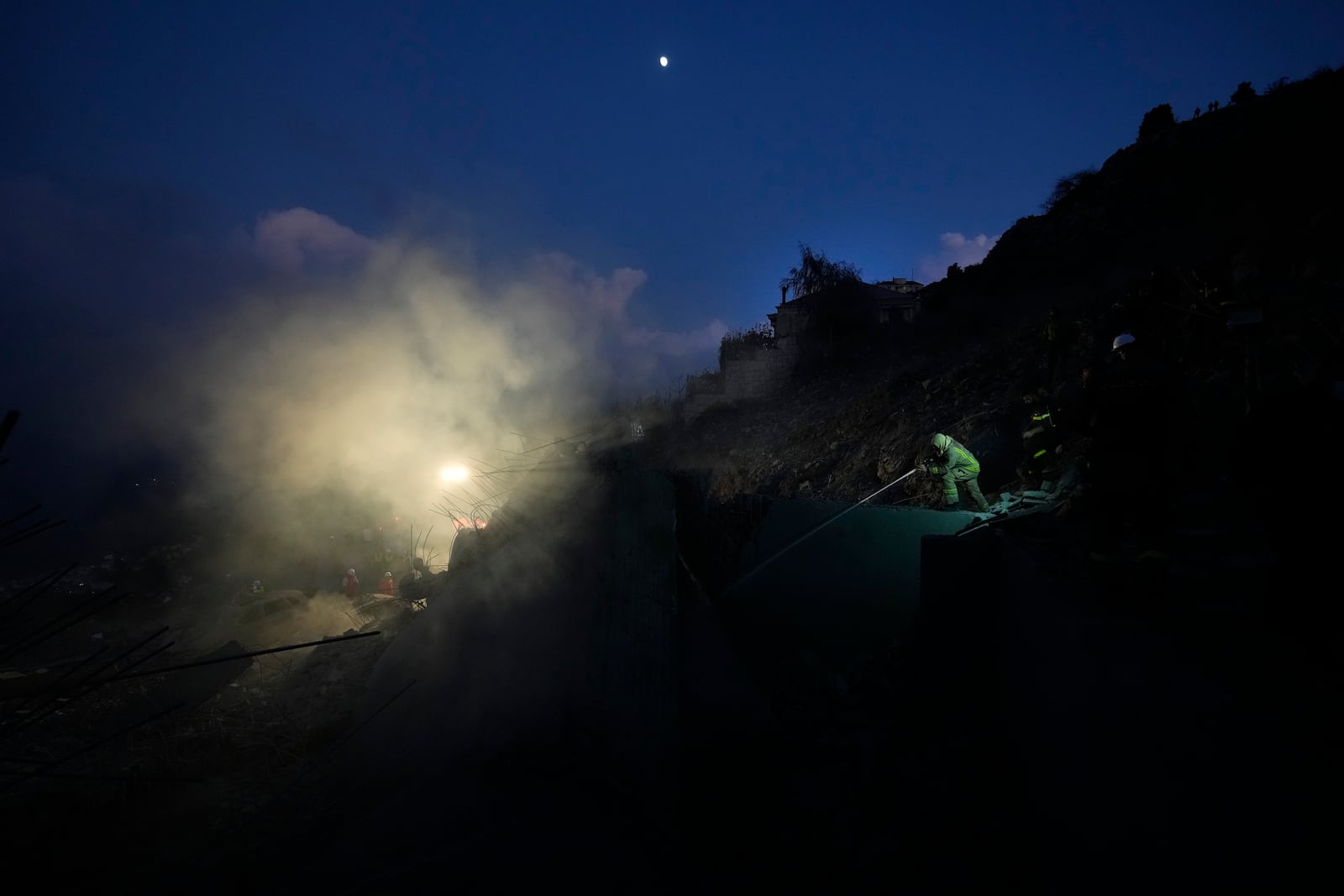 A firefighter, right, extinguishes a fire as smoke rises from a house hit in an Israeli airstrike in Baalchmay village east of Beirut, Lebanon, Tuesday, Nov. 12, 2024. (AP Photo/Hassan Ammar)