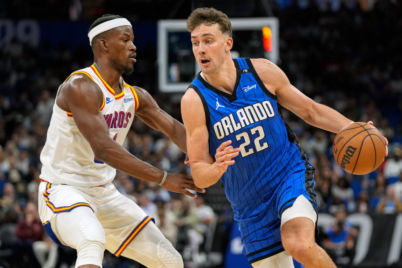 Orlando Magic forward Franz Wagner (22) drives past Golden State Warriors forward Jimmy Butler, left, during the first half of an NBA basketball game, Thursday, Feb. 27, 2025, in Orlando, Fla. (AP Photo/John Raoux)