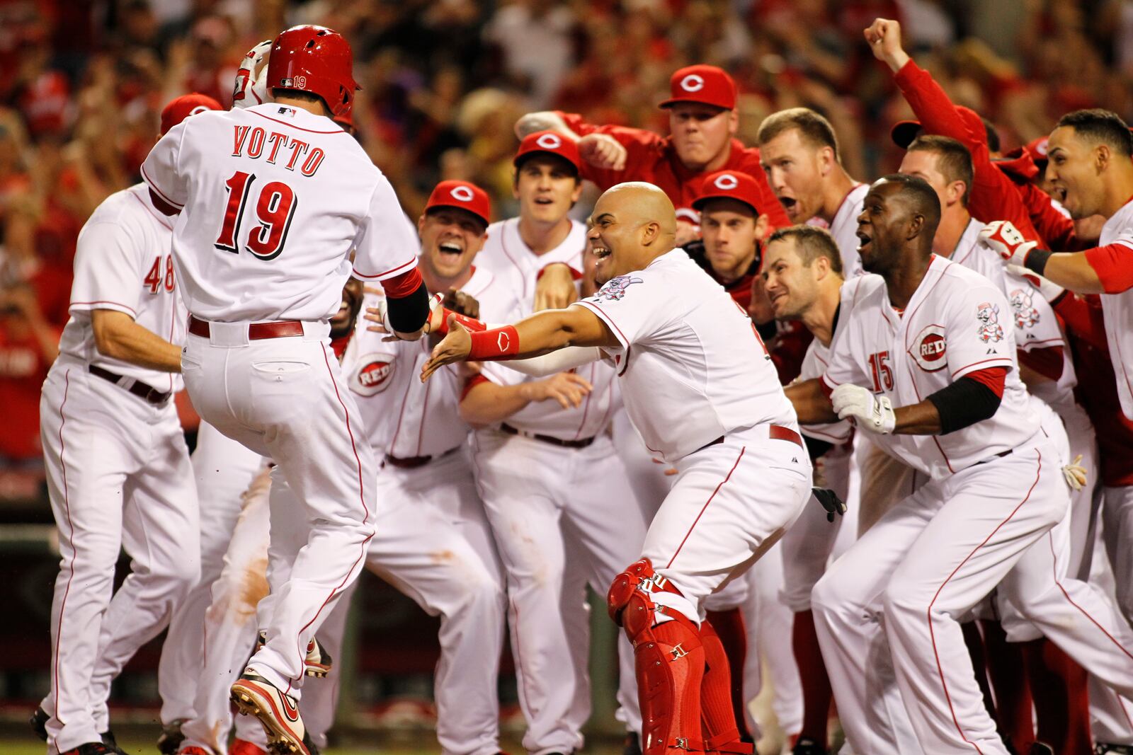 The Reds greet Joey Votto at home plate after his walk-off home run in the ninth beat the Rockies on Friday, May 9, 2014, at Great American Ball Park in Cincinnati. David Jablonski/Staff