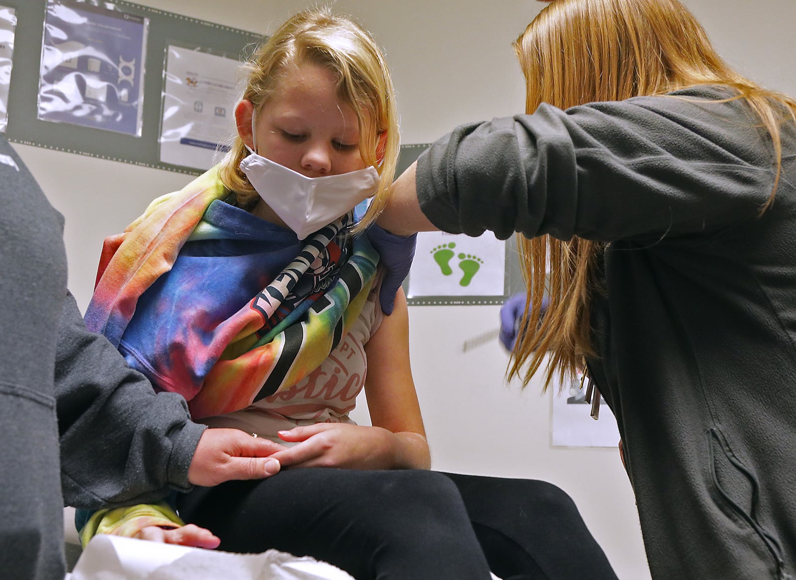 Hayley Chaney, 10, holds her mom's hand as she gets a COVID-19 vaccine shot at the Rocking Horse Center Monday. BILL LACKEY/STAFF