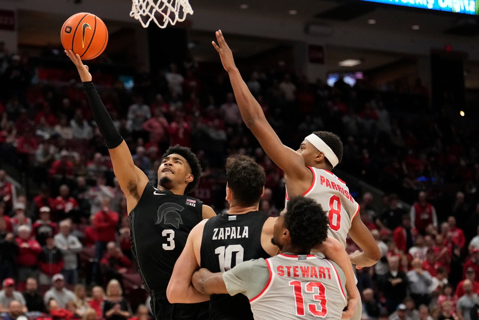 Michigan State guard Jaden Akins (3) shoots in front of Ohio State forward Sean Stewart (13), guard Micah Parrish (8) and teammate Szymon Zapala in the second half of an NCAA college basketball game Friday, Jan. 3, 2025, in Columbus, Ohio. (AP Photo/Sue Ogrocki)