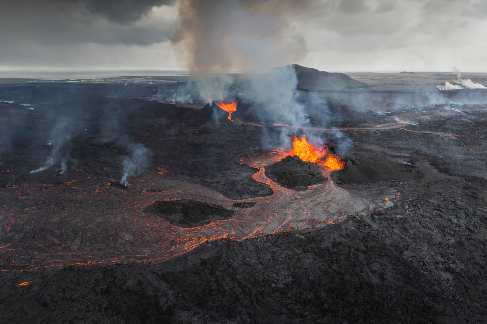 FILE - A panoramic view of the Svartsengi area with the active craters and lava flows in the foreground, near Grindavik, Iceland, Monday, June 3, 2024. The white steam in the top right is produced by the Powerplant and the Blue Lagoon area. (AP Photo/Marco di Marco, File)