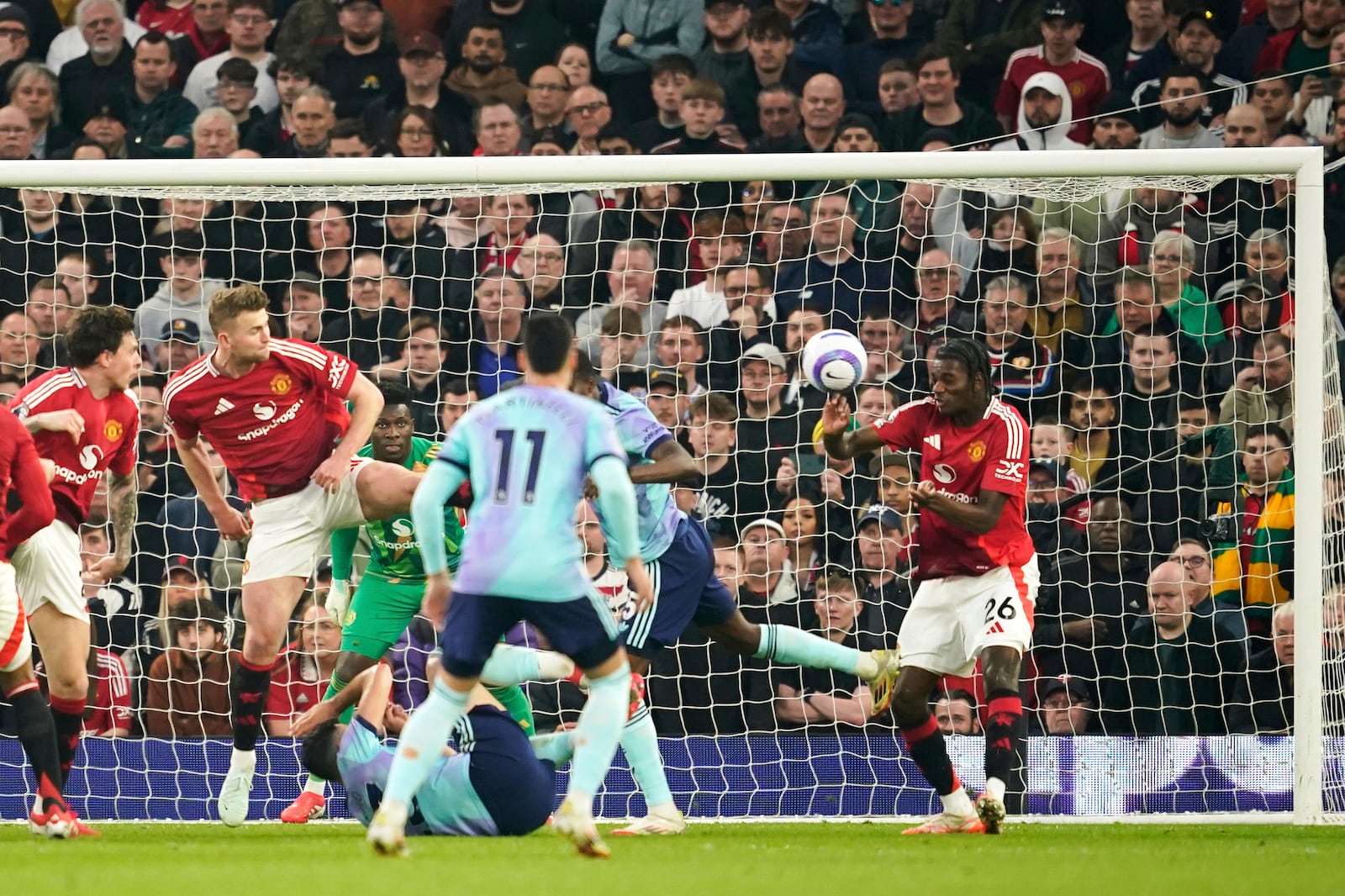 Manchester United's Ayden Heaven, right, clears the ball during the English Premier League soccer match between Manchester United and Arsenal at Old Trafford stadium in Manchester, England, Sunday, March 9, 2025. (AP Photo/Dave Thompson)