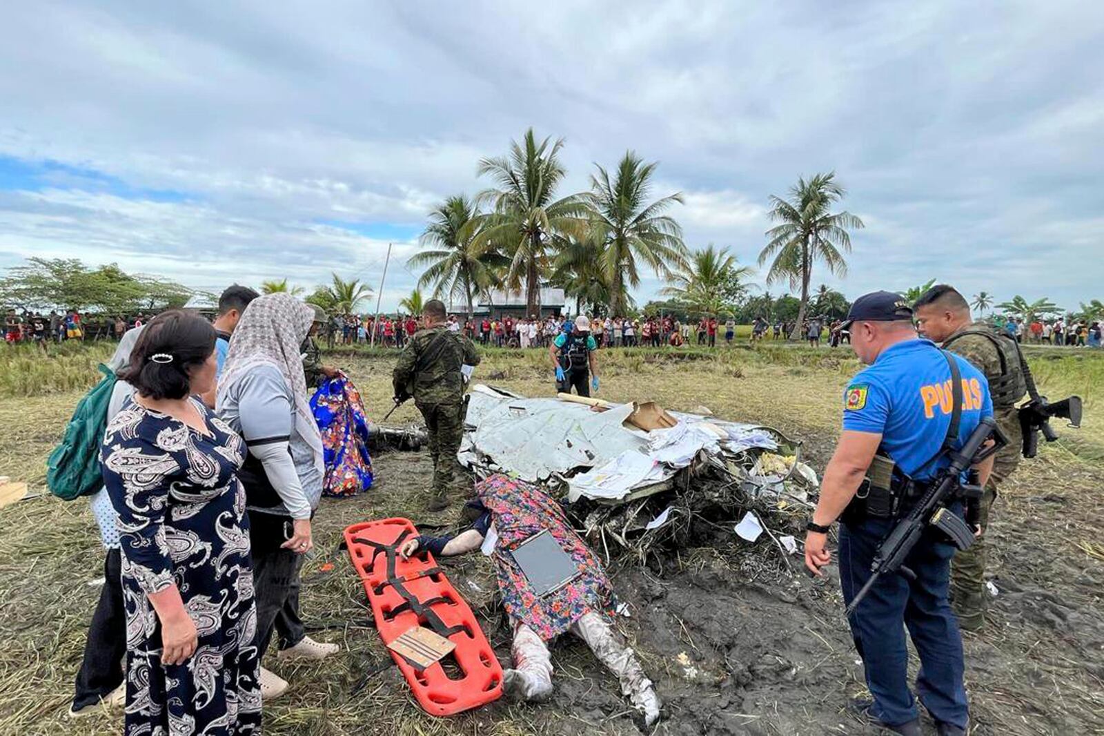 The body of a victim is covered with a blanket as members of security forces inspect the site where wreckage of airplane is seen in a rice field in Maguindanao del Sur province, Philippines, after officials say a U.S. military-contracted plane has crashed in a rice field in the southern Philippines, killing all four people on board, on Thursday Feb. 6, 2025. (Sam Mala/UGC via AP)