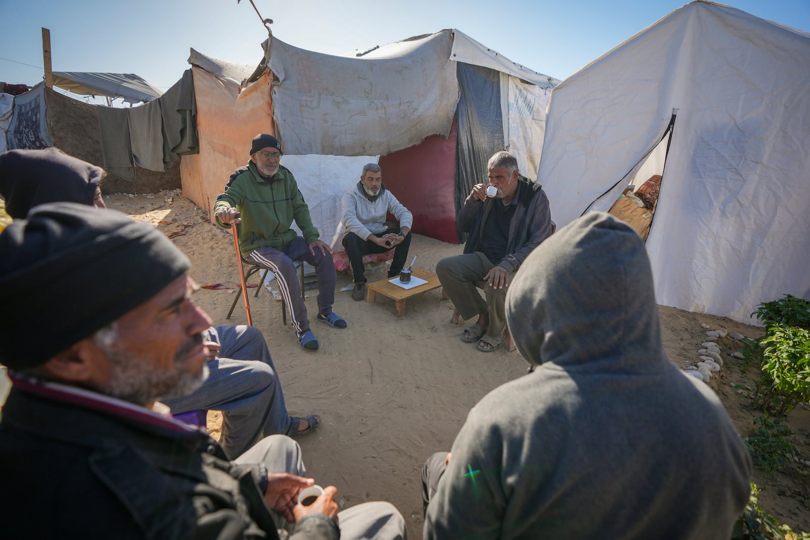 Tony Al-Masri, center left, sits with neighbours outside the tent he and his wife Amal Amouri, both Christians, share at the Muwassi tent camp near Khan Younis, Gaza Strip on Christmas Day Wednesday Dec. 25, 2024.(AP Photo/Abdel Kareem Hana)