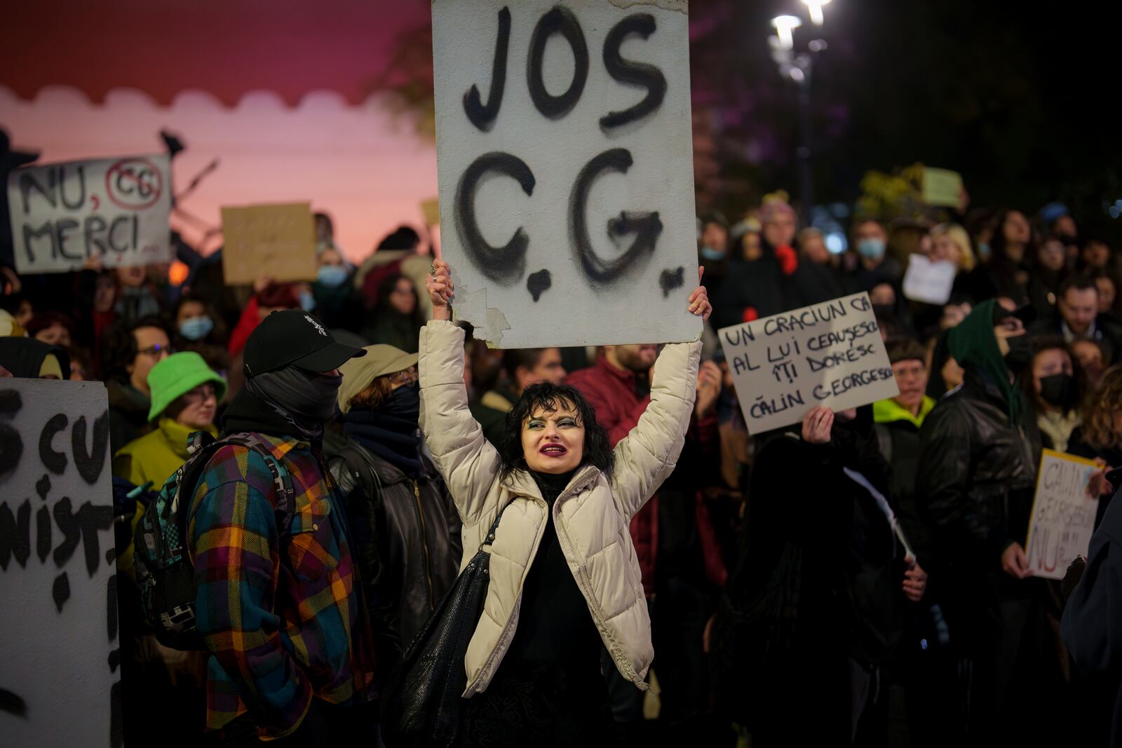 FILE - A woman holds a banner that reads "Down C. G." during a protest against Calin Georgescu, the independent candidate for Romanian presidency who won the first round of elections making it to the Dec. 8, runoff in Bucharest, Romania, Monday, Nov. 25, 2024. (AP Photo/Andreea Alexandru, FIle)