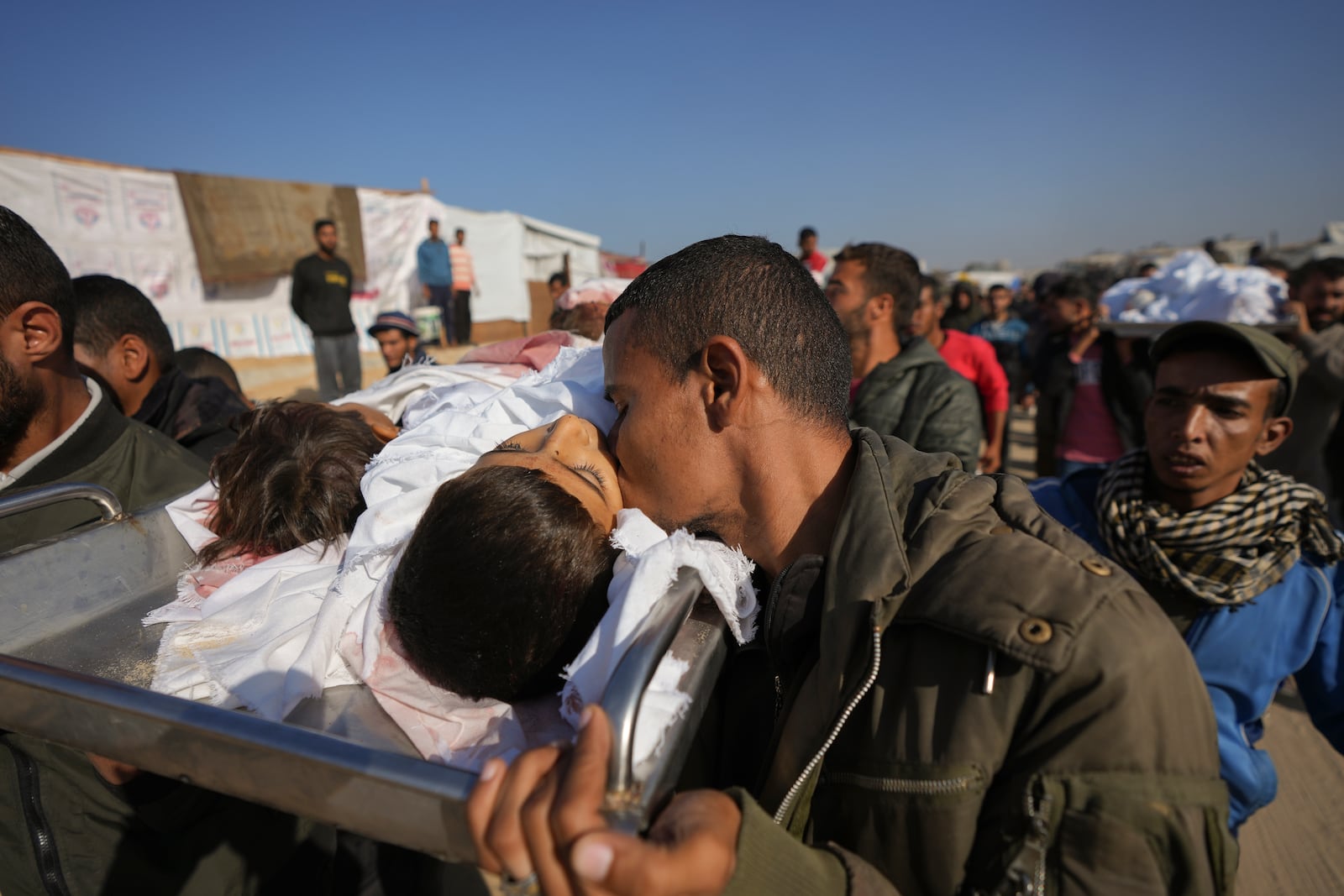 A man kisses the body one of three children as they are carried for burial in Deir al-Balah, Gaza Strip, Thursday Nov. 21, 2024. Seven-year-old Hamza, his five-year-old brother Abdelaziz, and his four-year-old sister Laila Hassan were among 9 people killed by an Israeli strike in Khan Younis on Wednesday. Palestinian health officials say the death toll in the Gaza Strip from the 13-month-old war between Israel and Hamas has surpassed 44,000. (AP Photo/Abdel Kareem Hana)