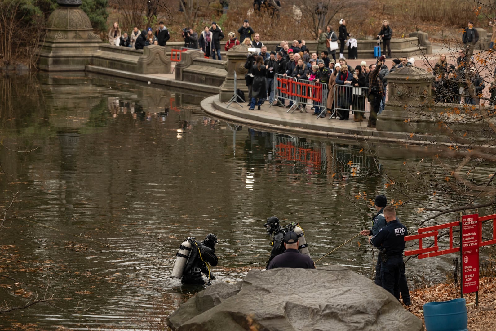 NYPD officers in diving suits search a lake in Central Park, Monday, Dec. 9, 2024, in New York. (AP Photo/Yuki Iwamura)