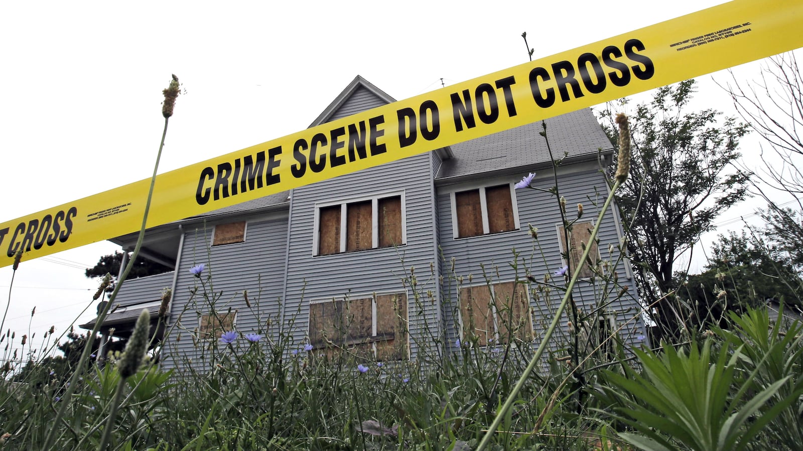 Crime scene tape cordons off a boarded-up home July 22, 2013, in an area where the bodies of three slain women were found in garbage bags in East Cleveland, Ohio. The mother of convicted serial killer Michael Madison, who was convicted in 2016 of the women's murders, was fatally stabbed to death in her home Saturday, June 22, 2019. Diane Madison's grandson has been charged in her killing and the stabbing of three of her young grandchildren.