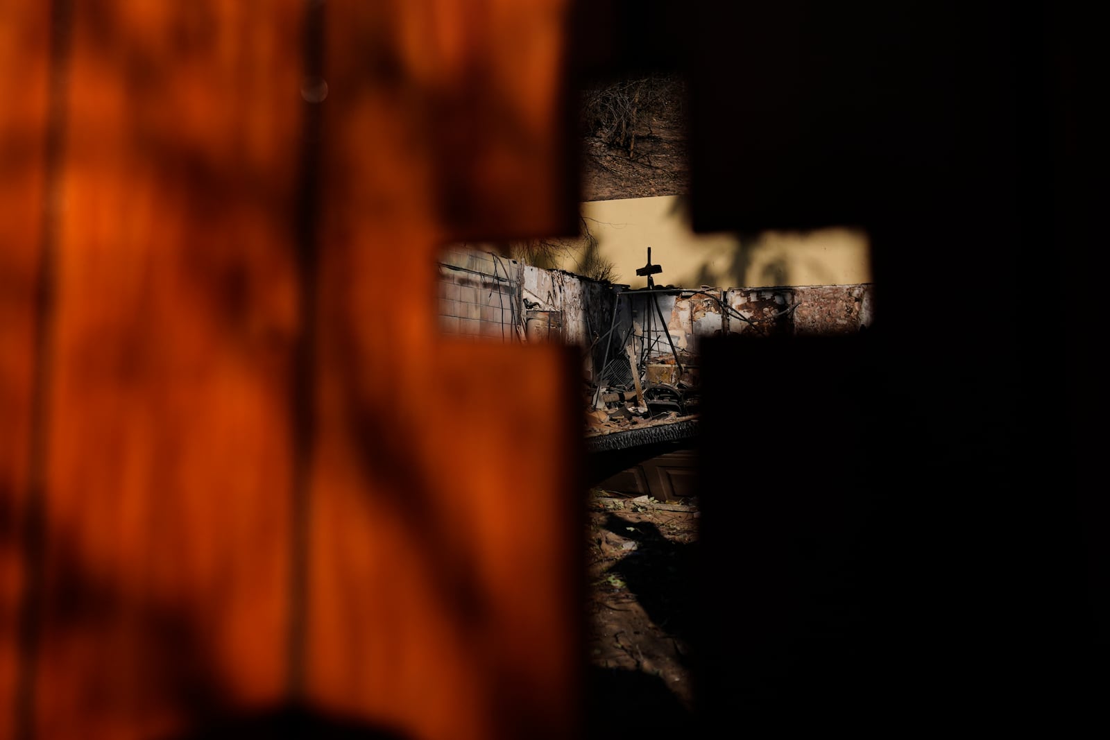 The remains of a home destroyed by the Eaton Fire are seen through a cross-shape, Thursday, Jan. 16, 2025, in Altadena, Calif. (AP Photo/Carolyn Kaster)